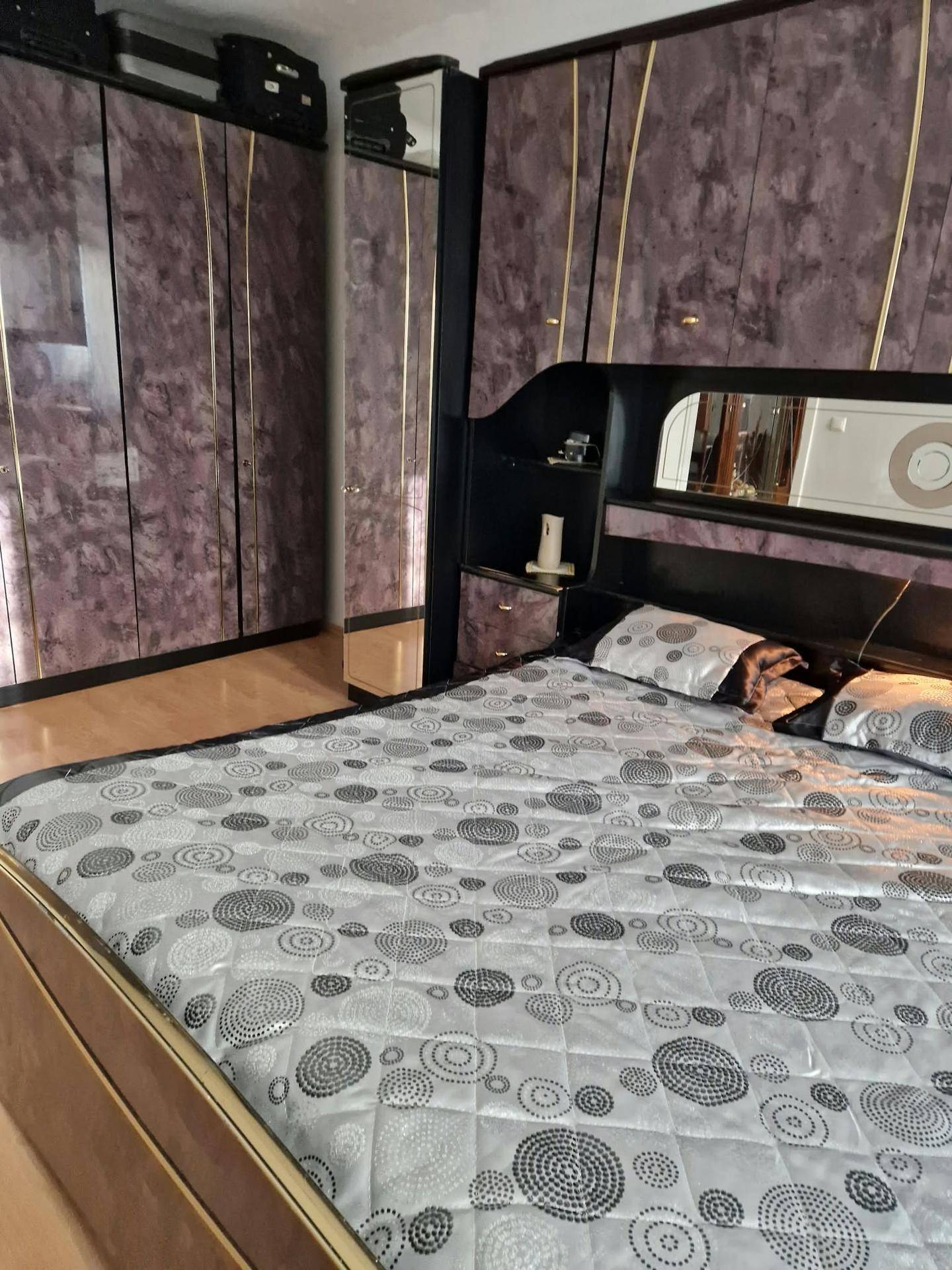 Schlafzimmer mit einem großen Bett, gemusterten Bettwaren und dunklen, gemaserten Kleiderschränken.