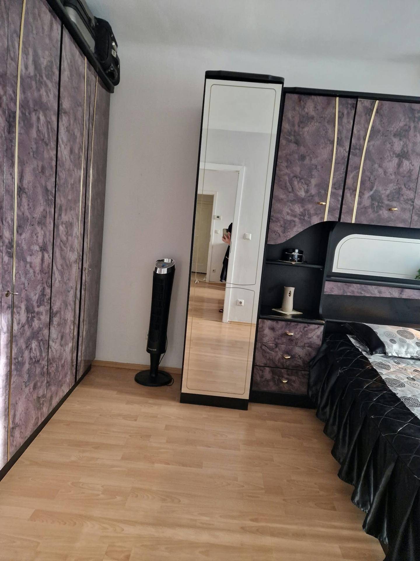 Schlafzimmer mit einem großen Bett, geräumigen Kleiderschränken und einem praktischen Ganzkörperspiegel.