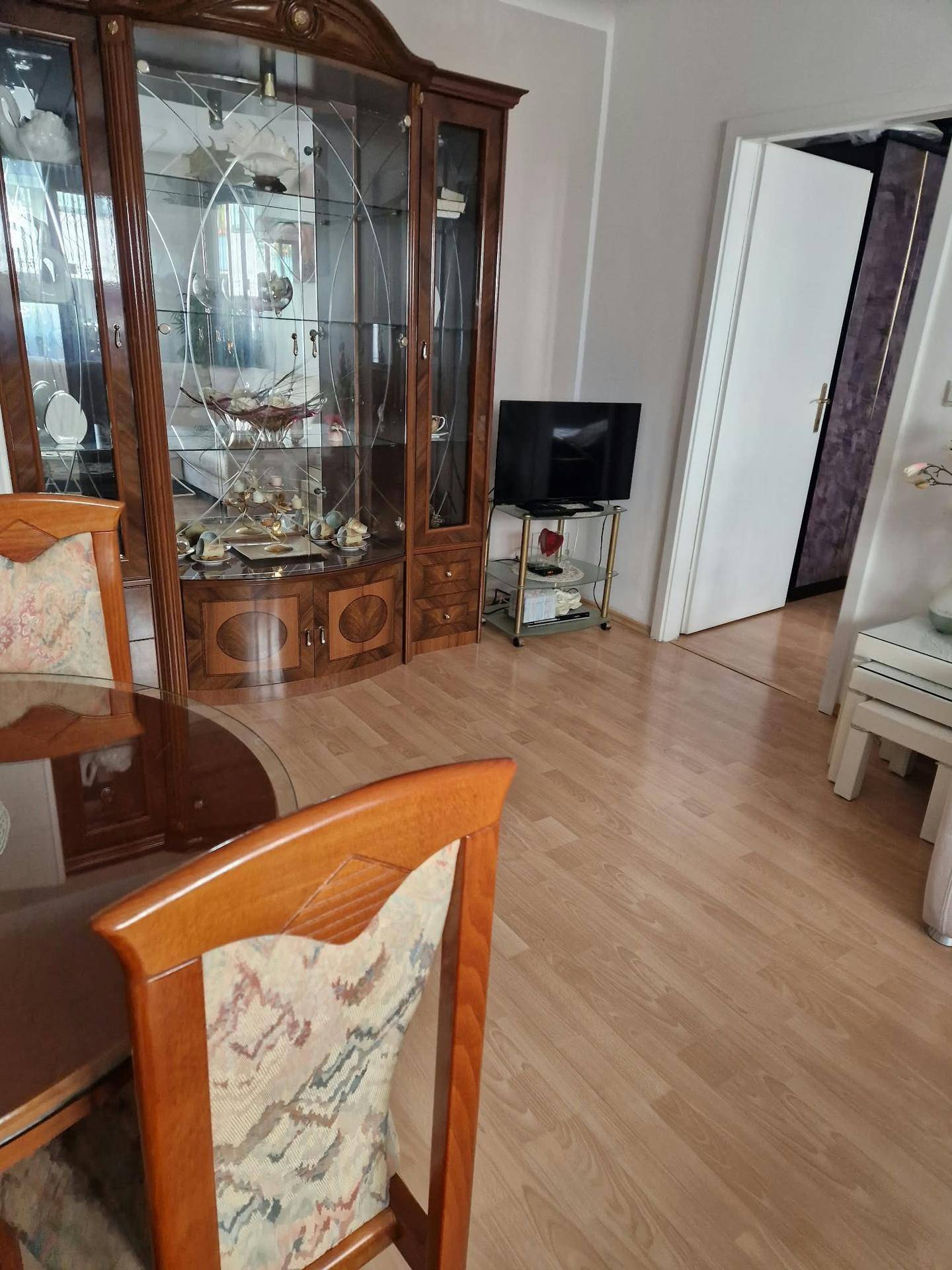 Essbereich mit klassischem Holztisch, Stühlen und einer großen Vitrine, die den Übergang zum Wohnbereich andeutet.