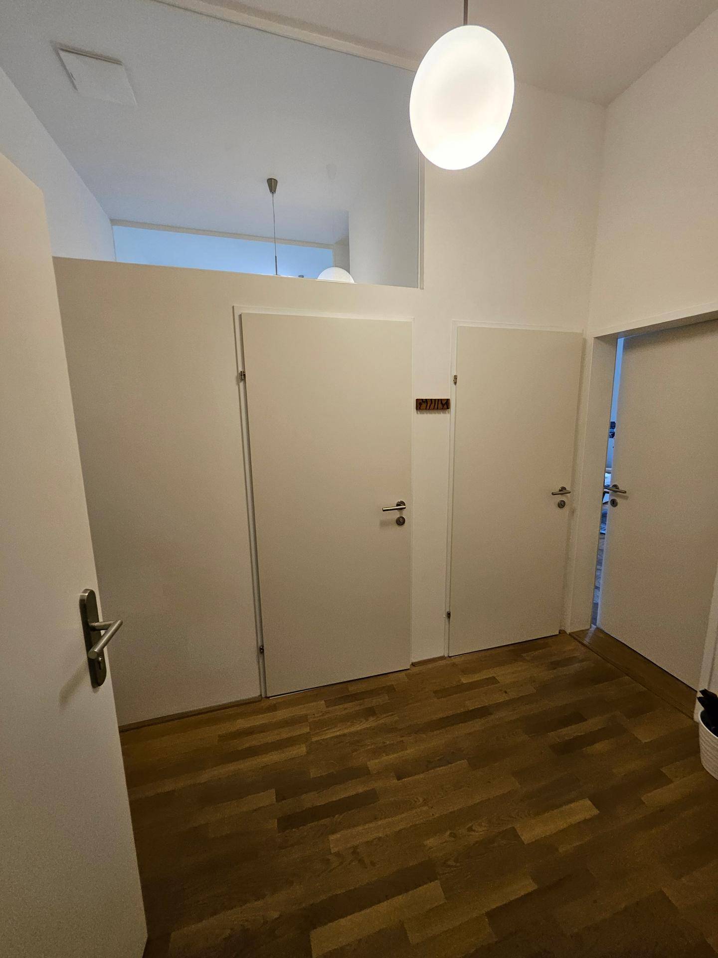 Geräumiger Flur mit Holzfußboden und mehreren Türen zu den angrenzenden Räumen.