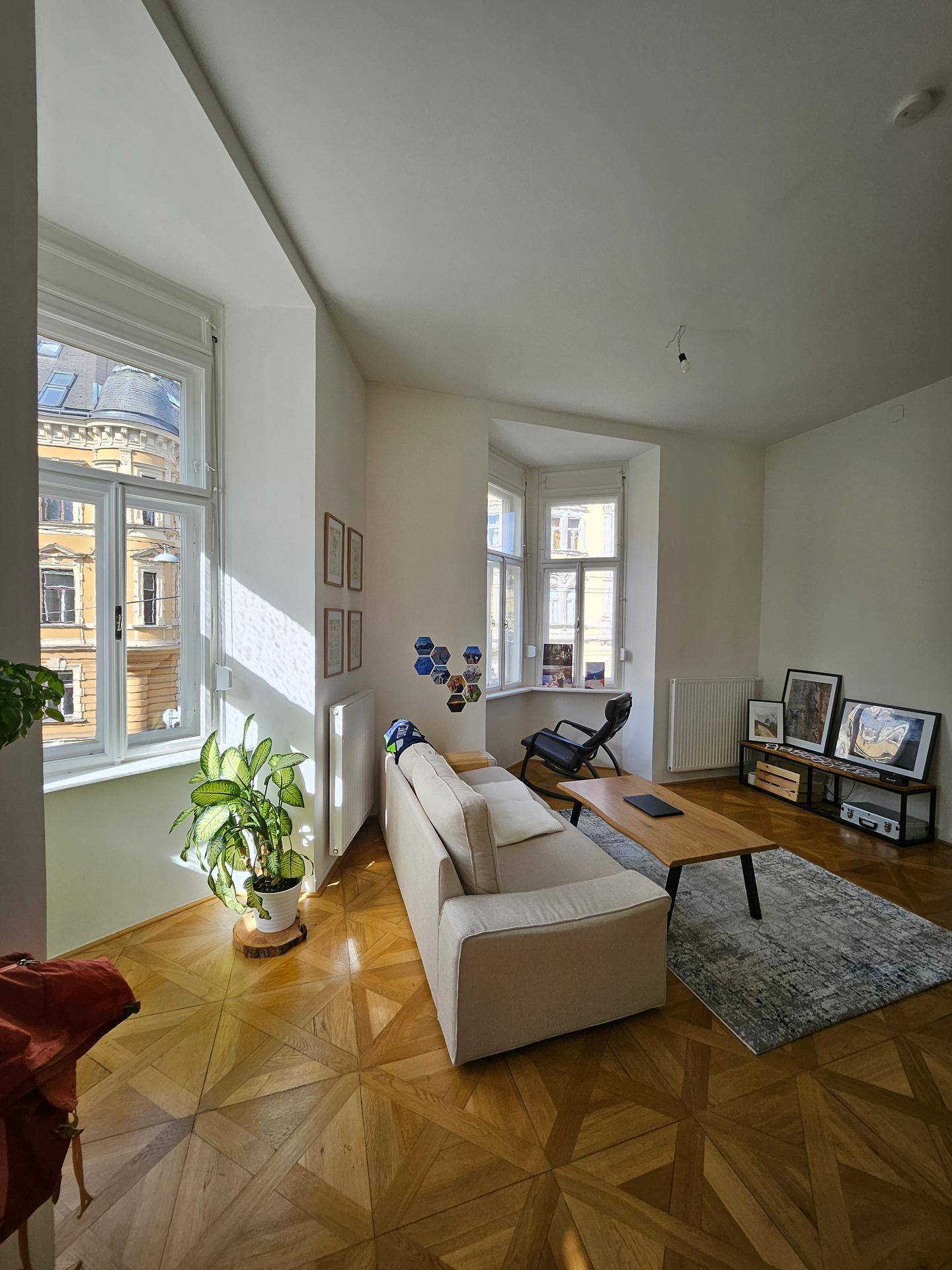 Lichtdurchflutetes Wohnzimmer mit elegantem Parkettboden und gemütlicher Sitzecke.