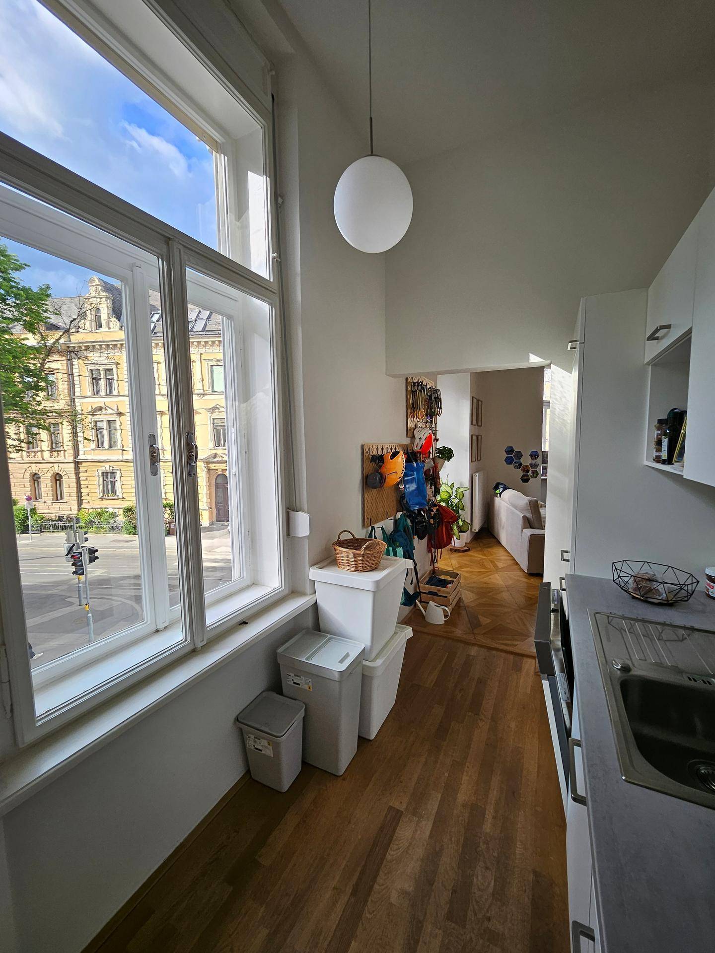 Küche mit Fensterblick auf die Straße und Übergang zu einem hellen Flurbereich.