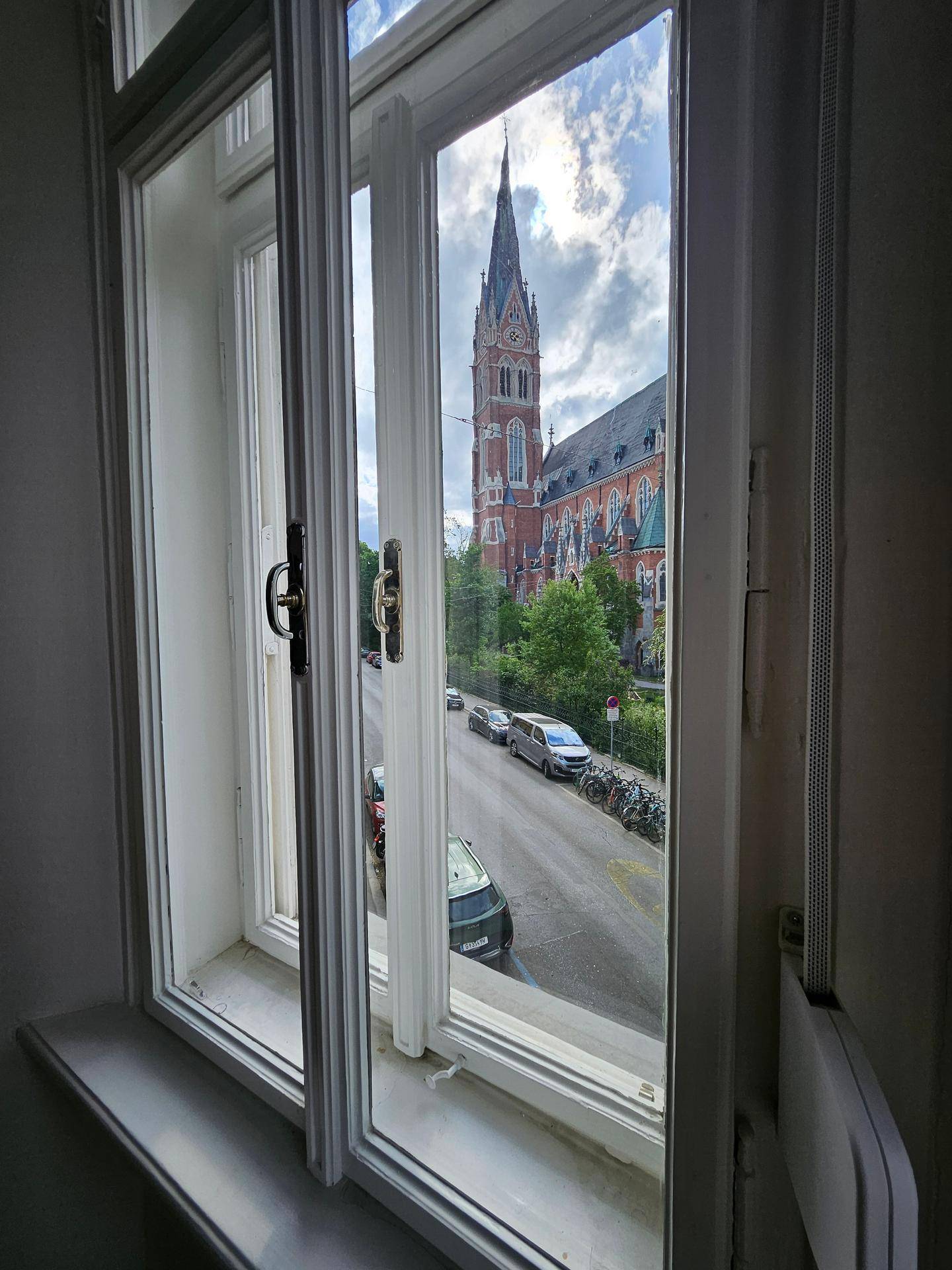 Blick aus dem Fenster auf eine beeindruckende Kirche mit hohem Turm und die belebte Straße.