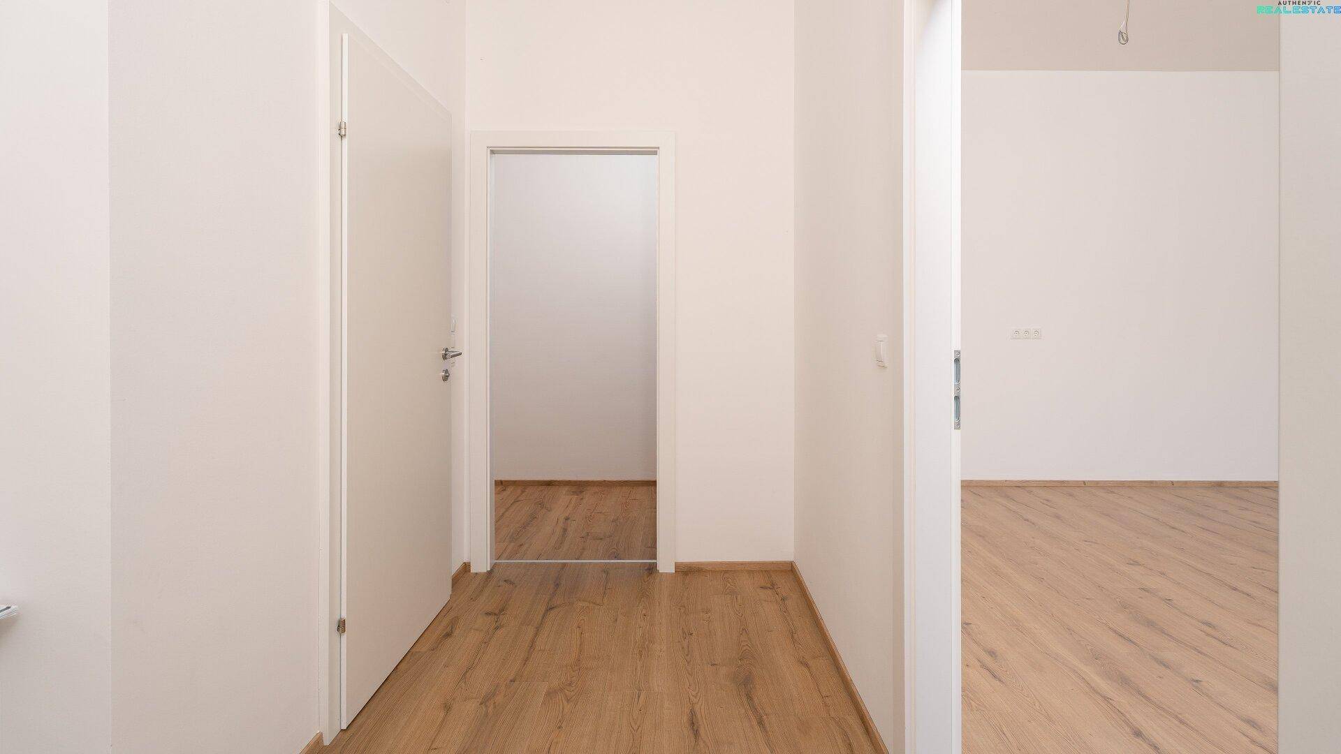 Heller Flur mit Laminatboden und weißen Türen, der zu weiteren Räumen führt.