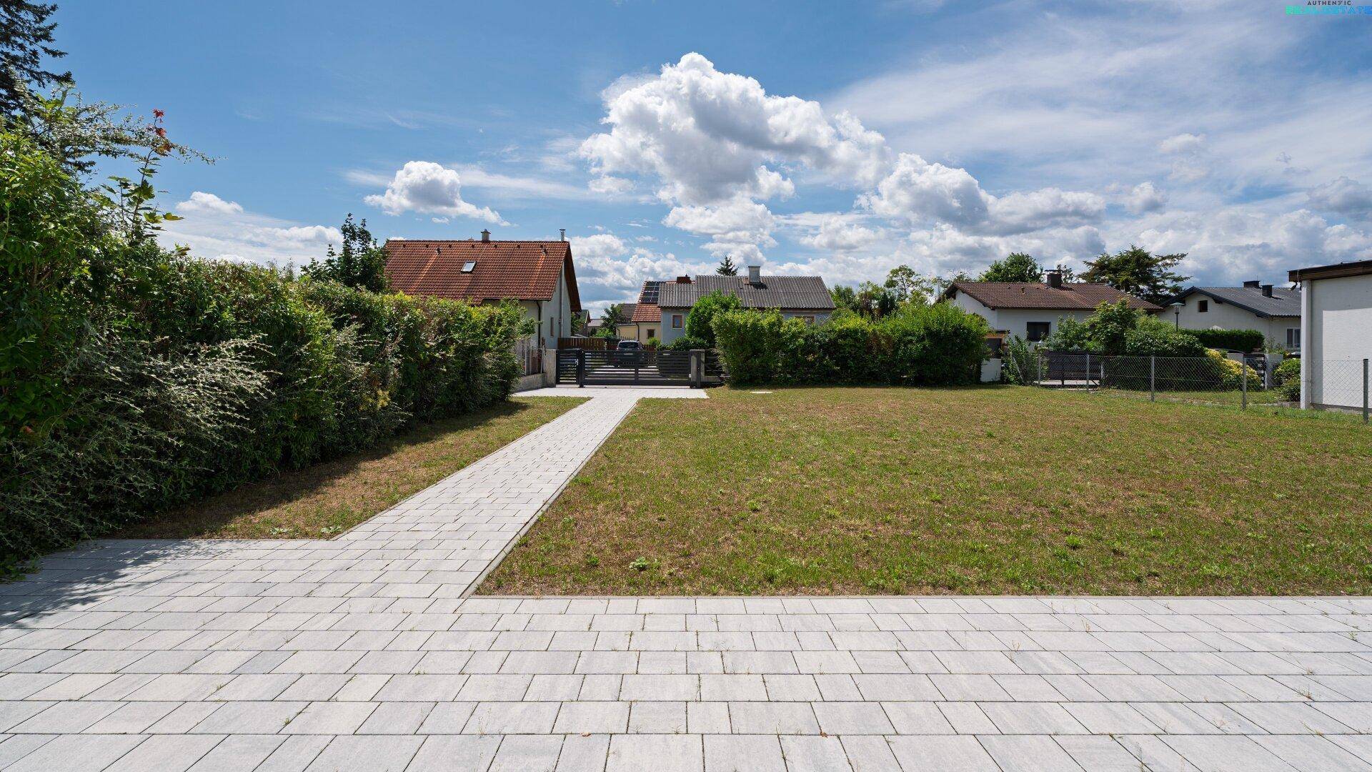 Großer Rasenbereich mit gepflastertem Weg und Blick auf die Nachbarschaft.