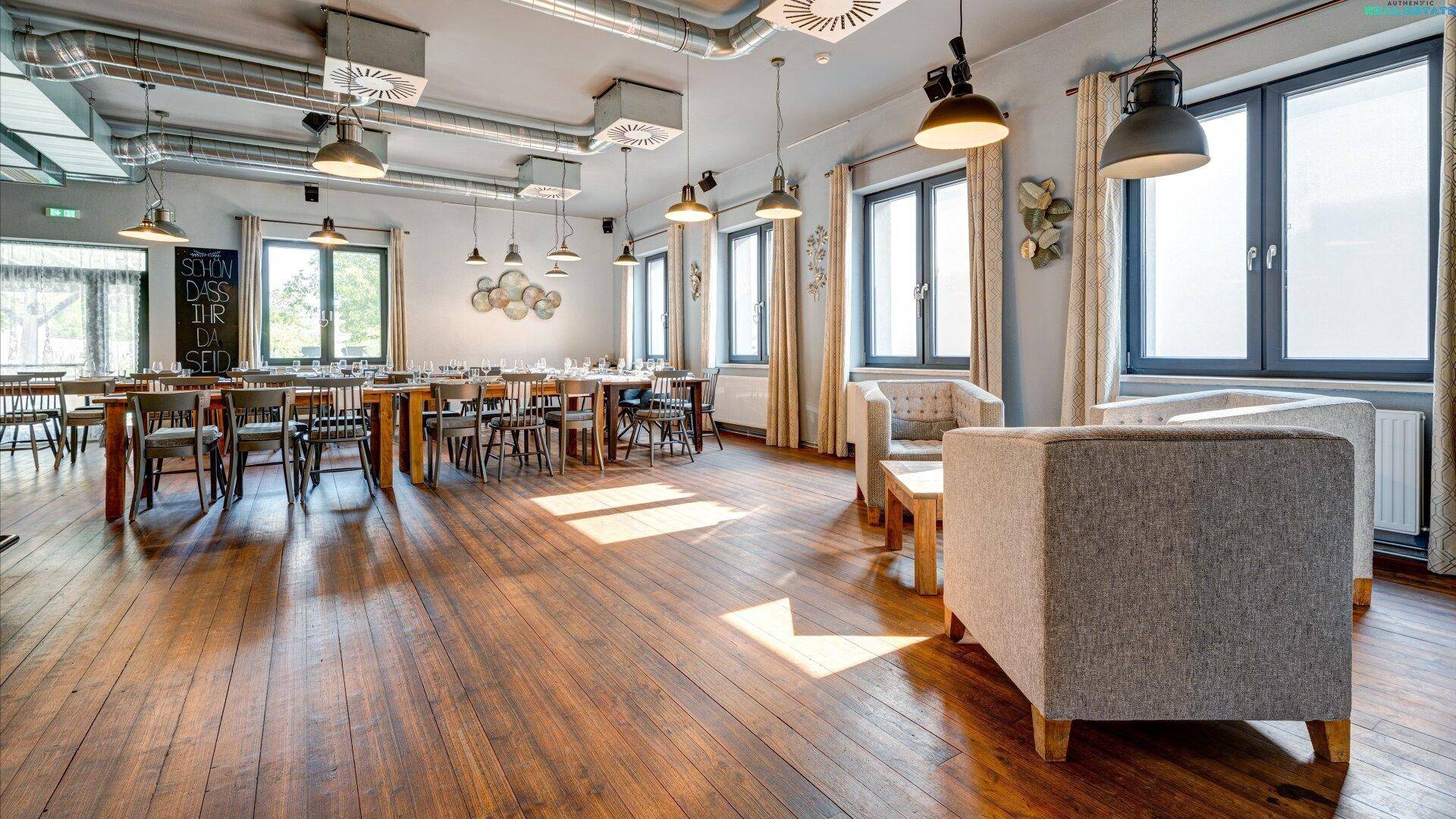 Großer Veranstaltungsraum mit Holzboden, Essbereichen und einer gemütlichen Lounge-Ecke.