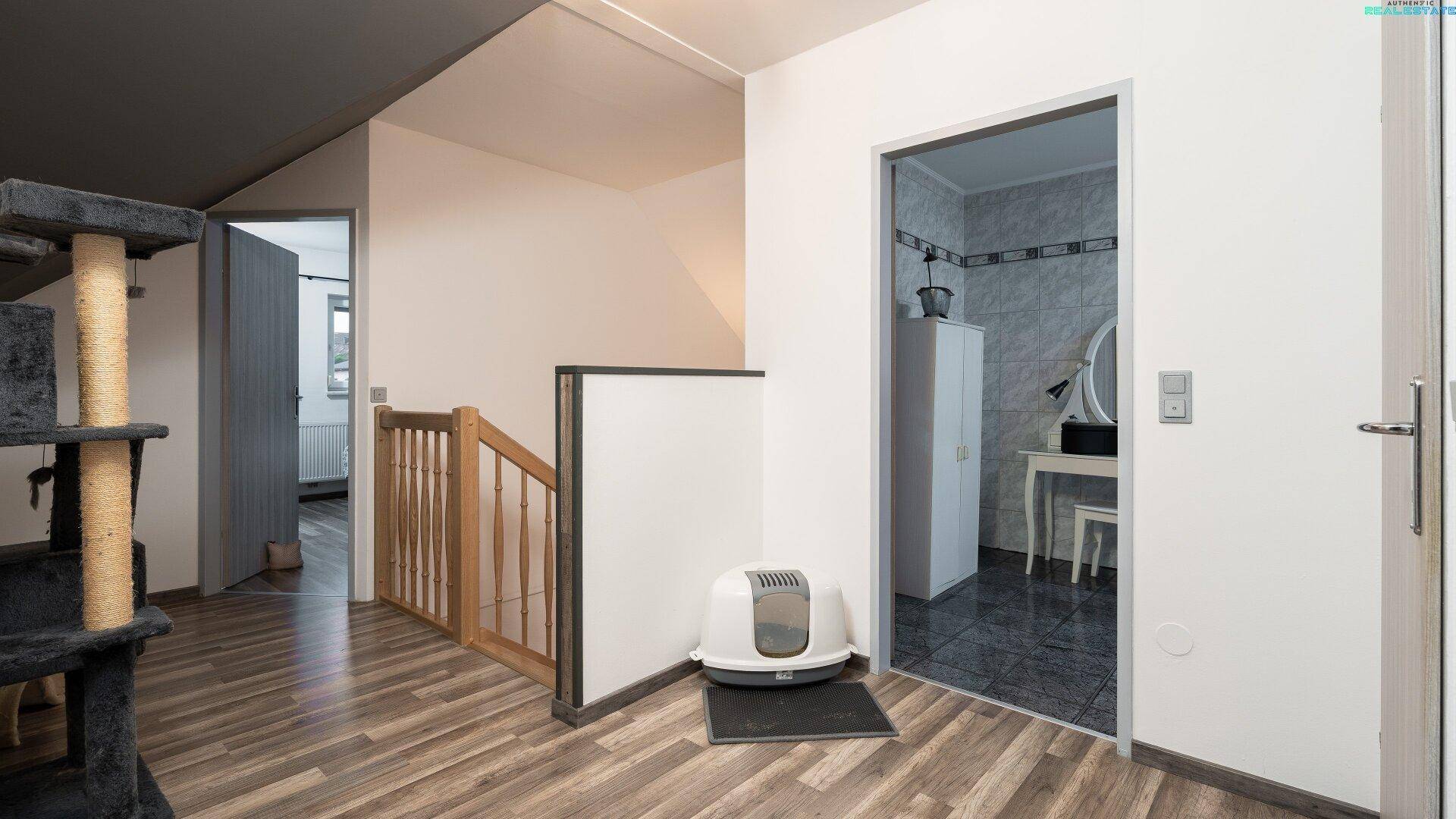Heller Flur im Obergeschoss mit Zugang zum Badezimmer und Dachschrägen.