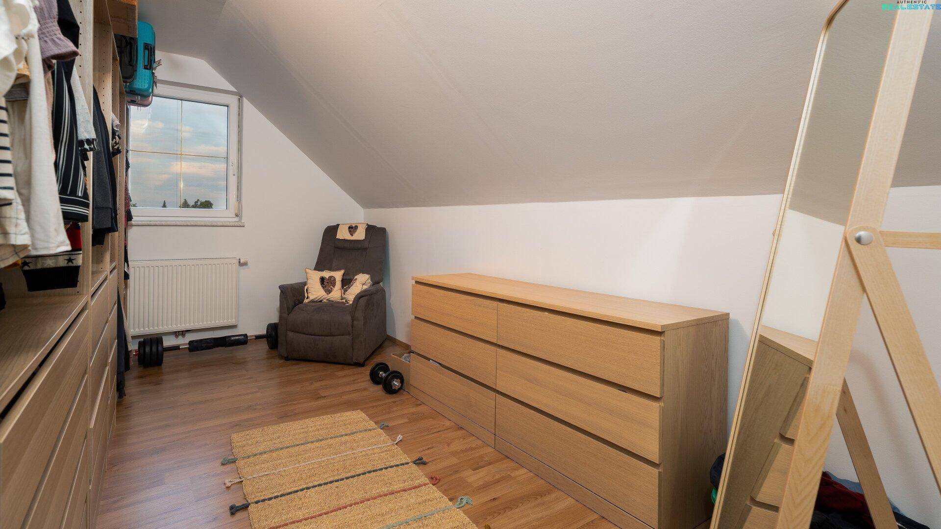 Ankleidezimmer mit eingebauten Kommoden, Spiegel und Dachschrägen.