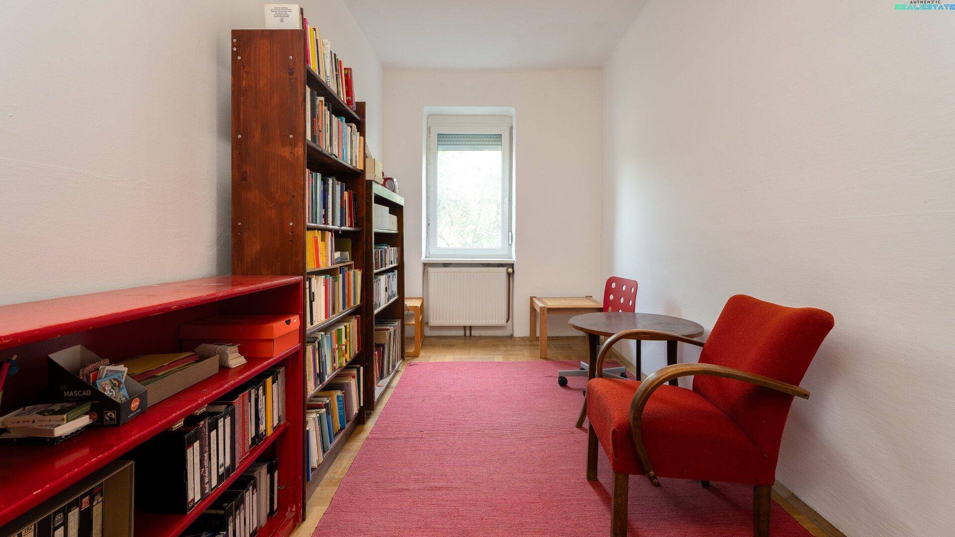 Ruhiger Raum mit Bücherregalen, kleinem Tisch und rotem Teppichboden.