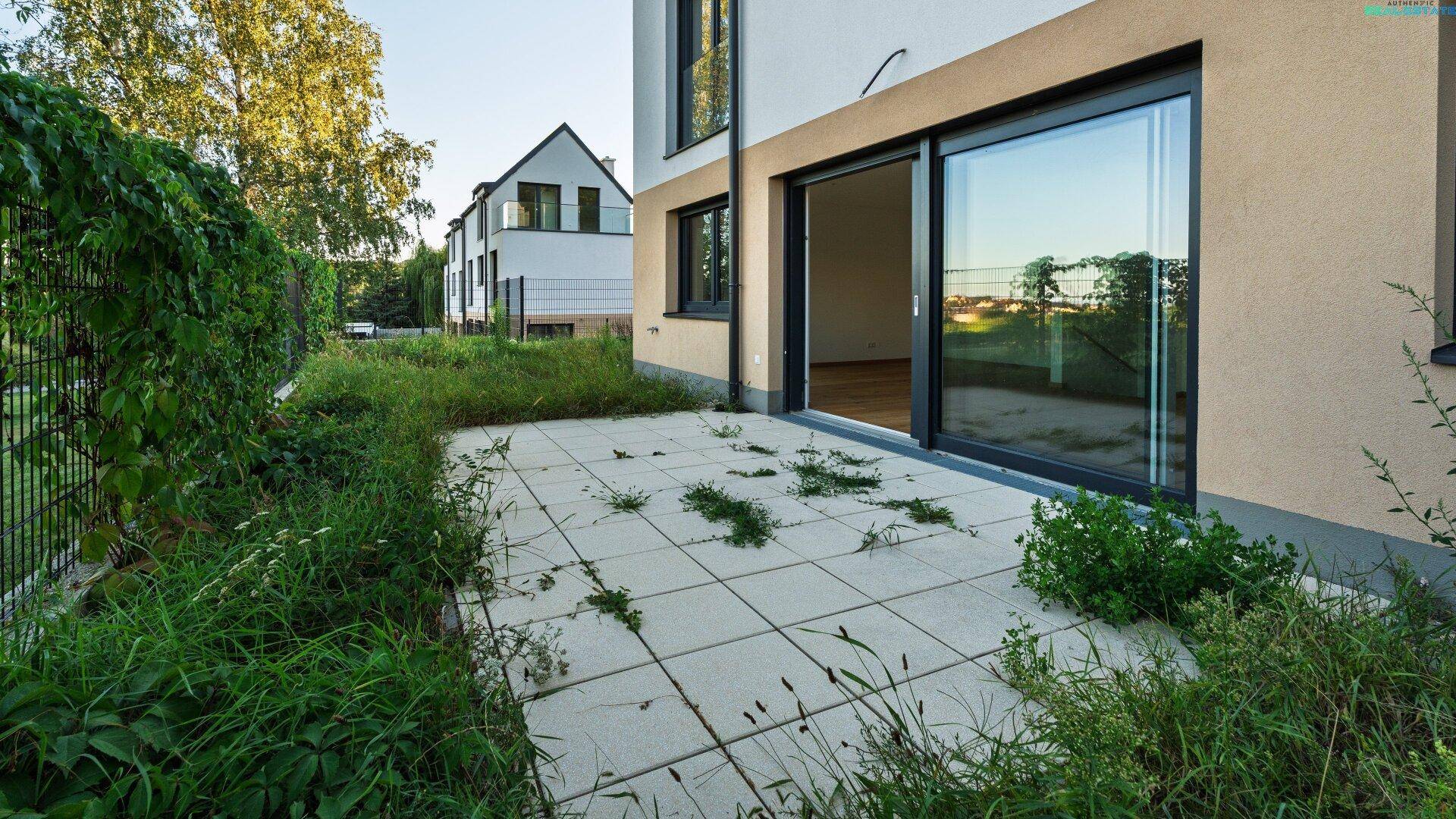 Terrasse mit großen Schiebetüren zum Innenbereich und Blick ins Grüne, umgeben von Natur.