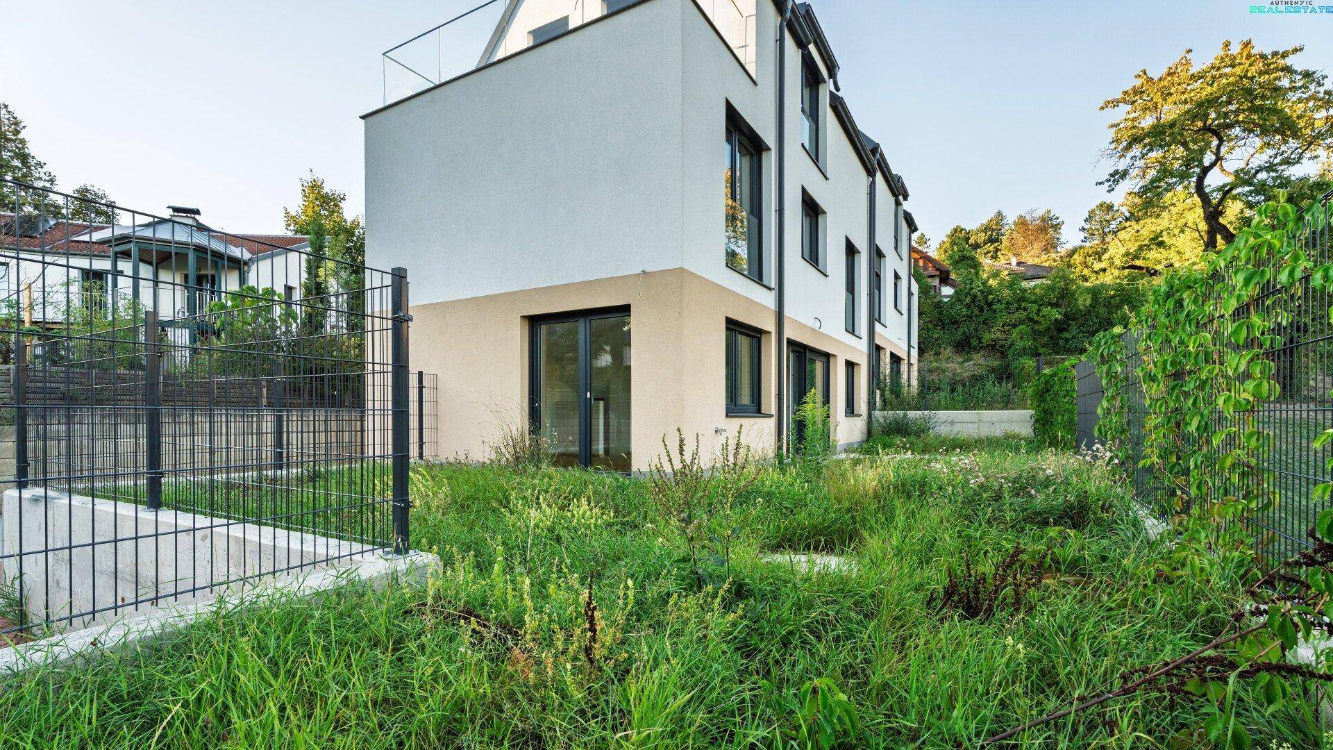 Seitenansicht des Neubaus mit großem, naturbelassenem Gartenbereich und Blick auf die Umgebung.