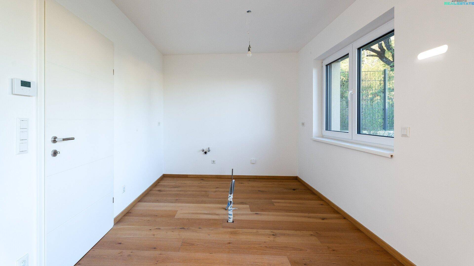 Leeres Zimmer mit Holzboden, Fenster und viel Tageslicht, ideal als Schlaf- oder Arbeitszimmer.