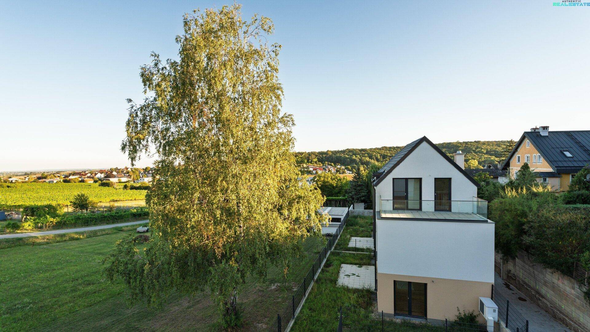 Modernes Wohnhaus mit Flachdach und großem Gartenbereich in ländlicher Umgebung.