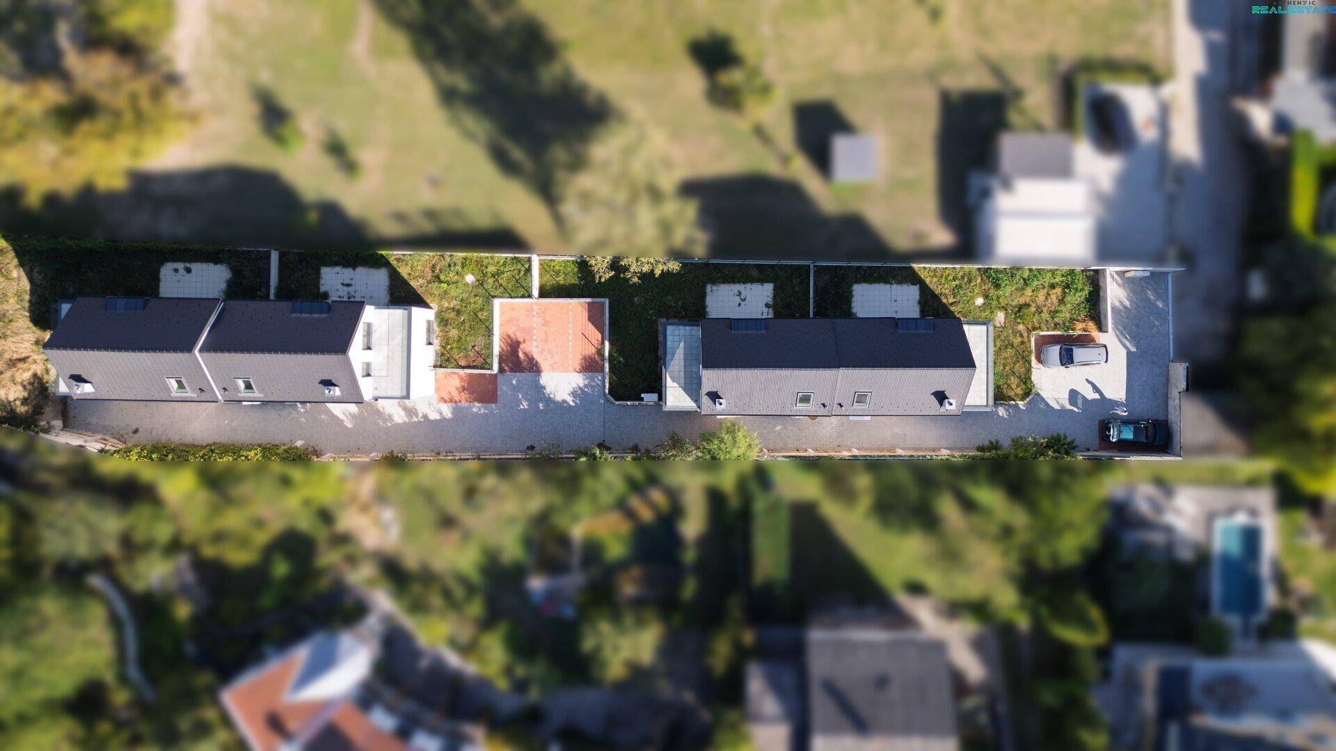 Vogelperspektive der Wohnanlage mit Häusern, Gärten und Parkplätzen in einer grünen Umgebung.