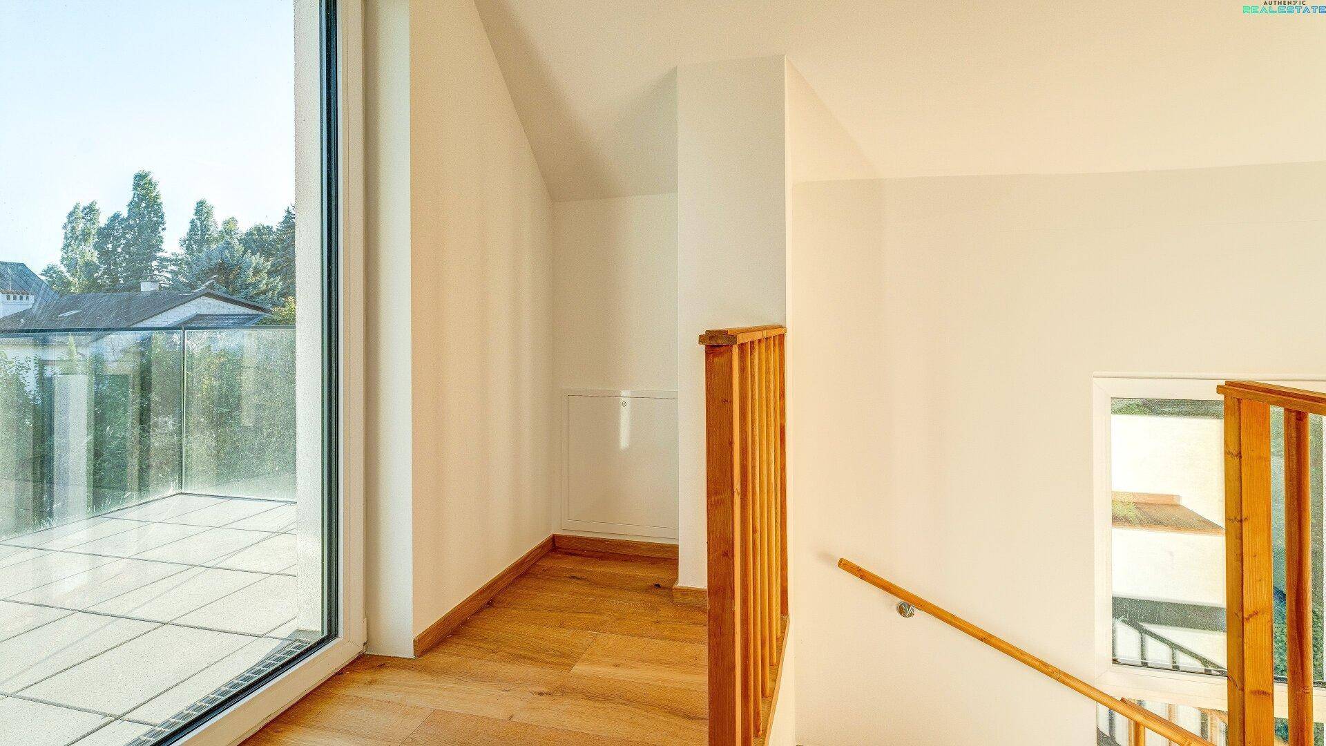 Heller Treppenabsatz mit Holzboden und Zugang zur Dachterrasse, bietet viel natürliches Licht.
