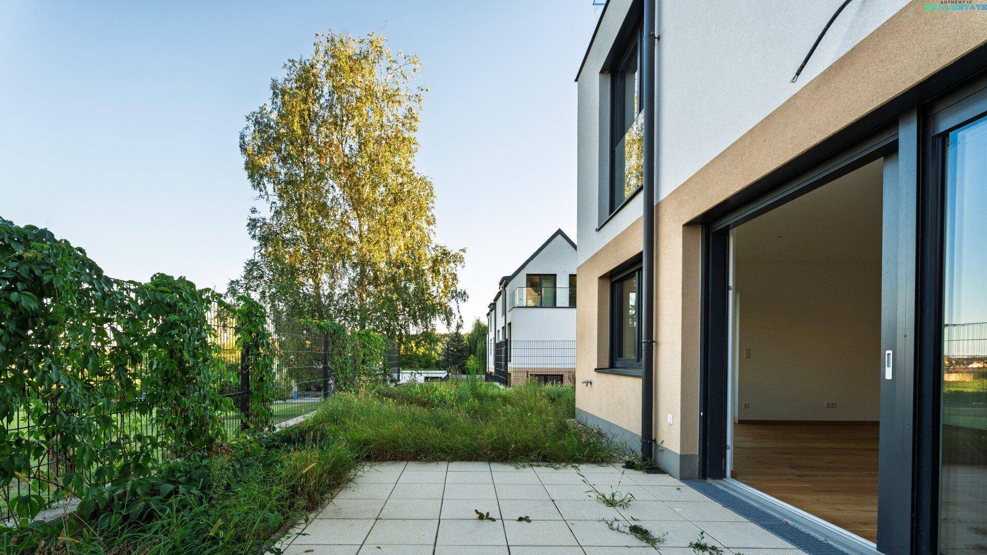 Helle Terrasse mit Zugang zum Garten und Blick auf die umliegende grüne Landschaft.