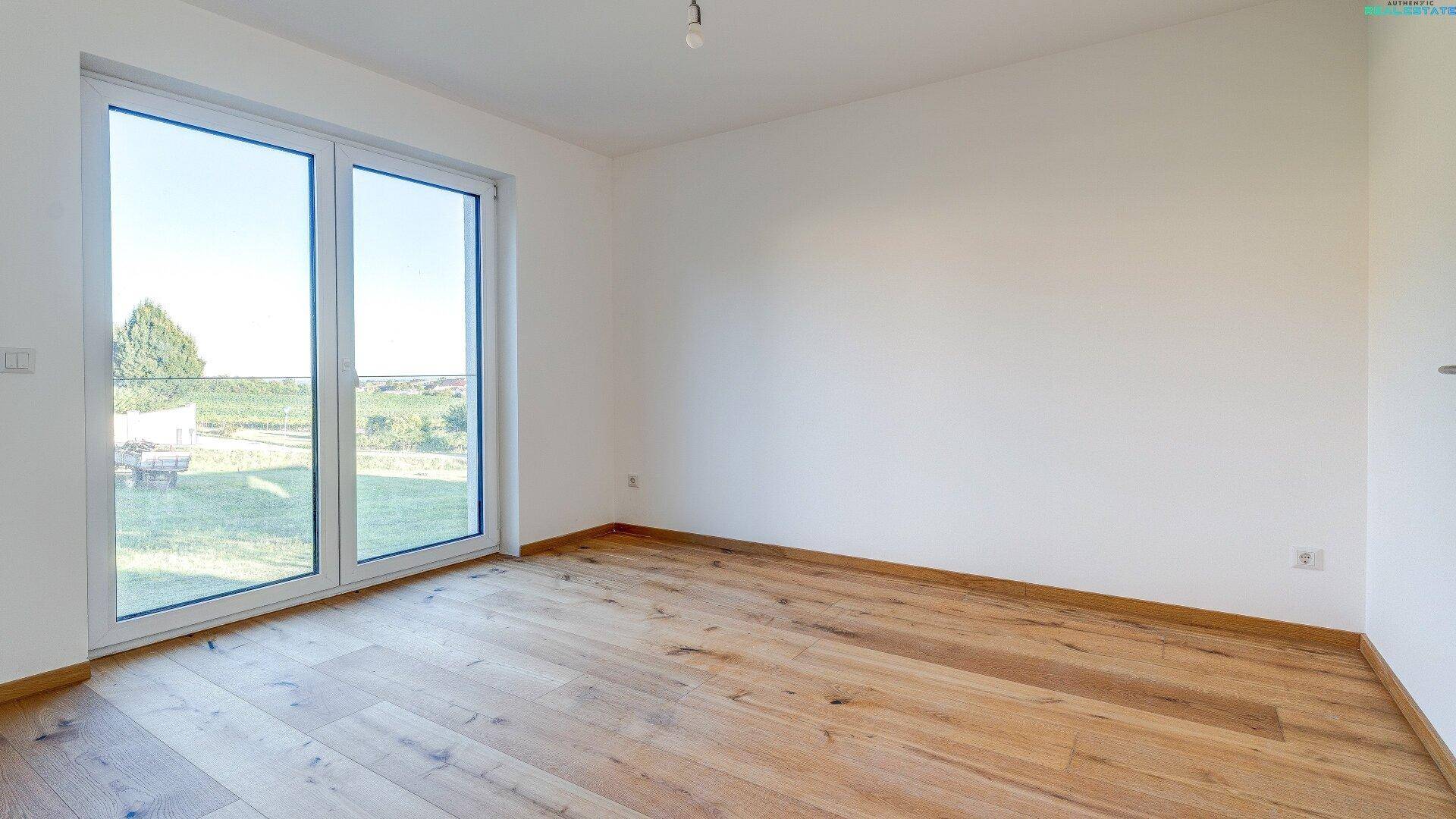 Helles Schlafzimmer mit großem Fenster und Zugang zu einem möglichen Balkon oder Terrasse.