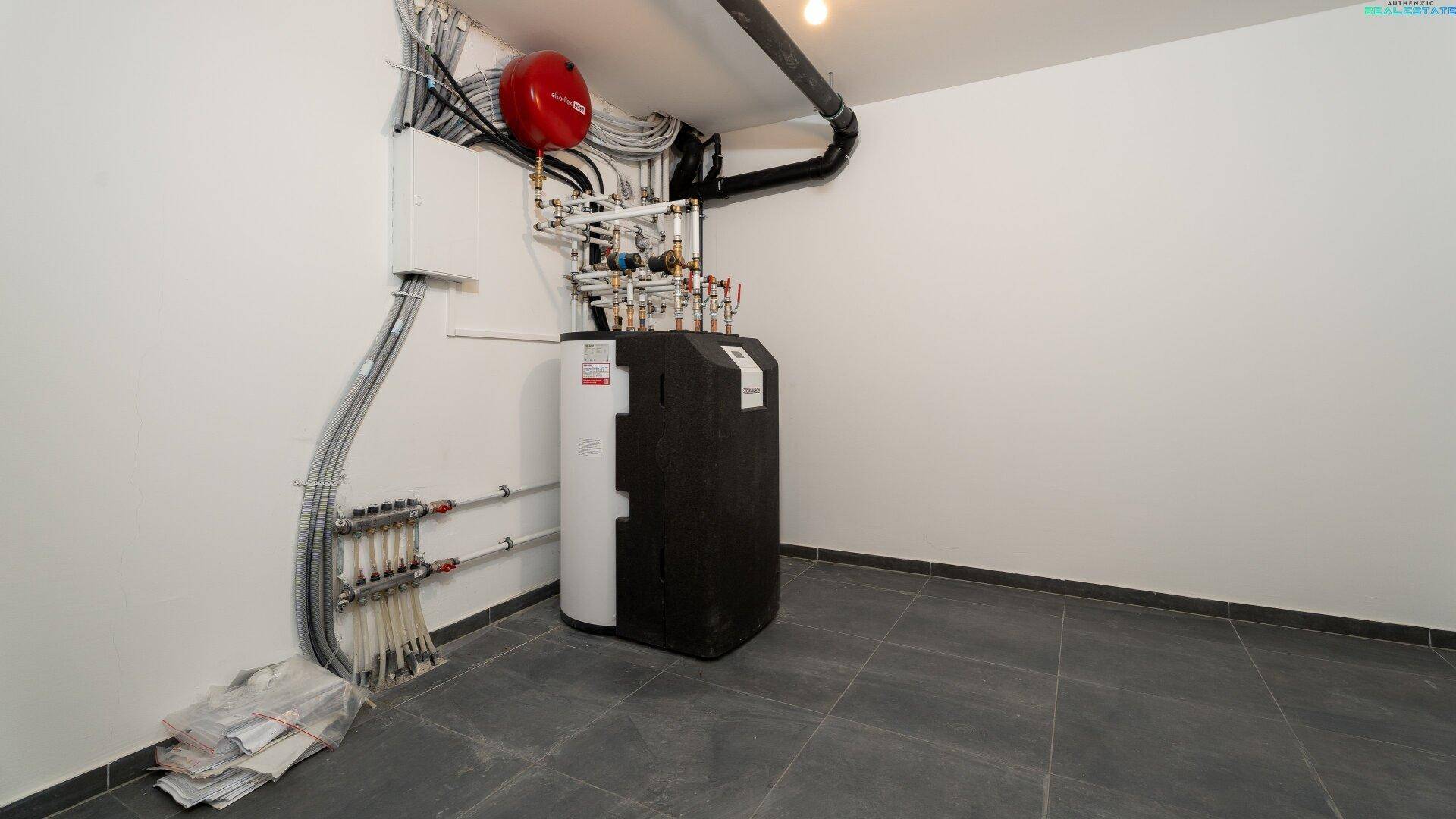 Technikraum mit Heizungsanlage und Leitungen, ausgestattet mit Fliesenboden.