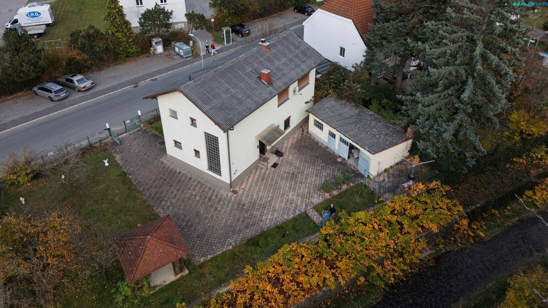Luftaufnahme des Anwesens mit Haus, Garage, Garten und der umliegenden ländlichen Landschaft.