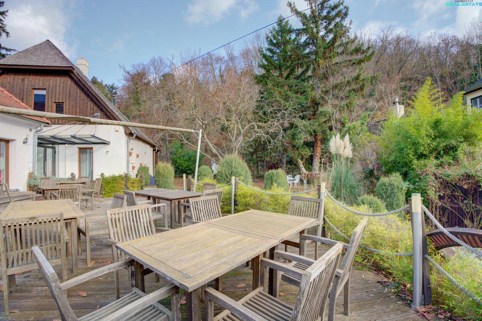 Gemütliche Holzterrasse mit Sitzgelegenheiten und Blick auf die bewaldete Umgebung und den Garten.