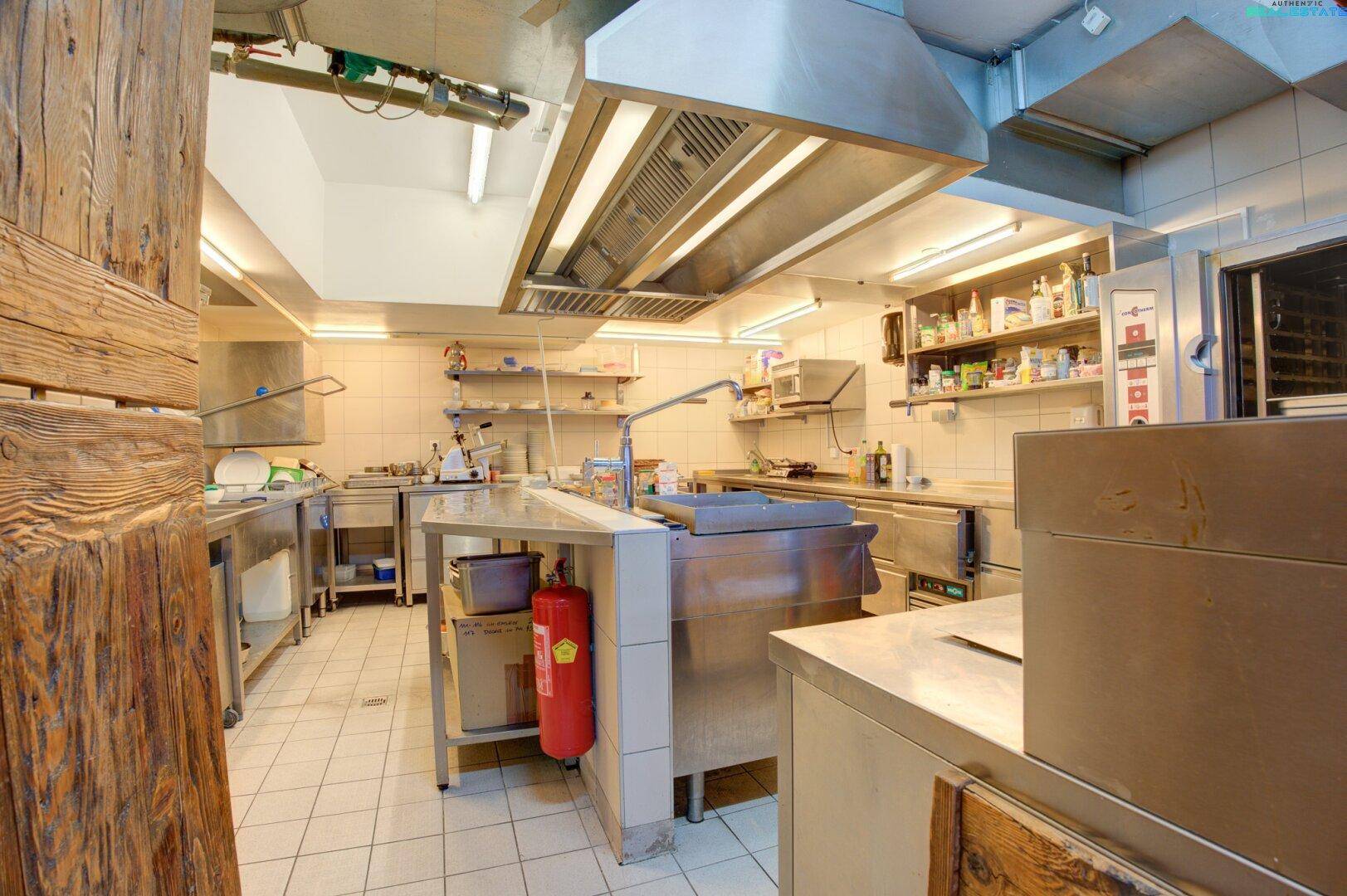 Professionelle Großküche mit Edelstahloberflächen und Abluftanlage, gut ausgestattet für den Gastronomiebetrieb.