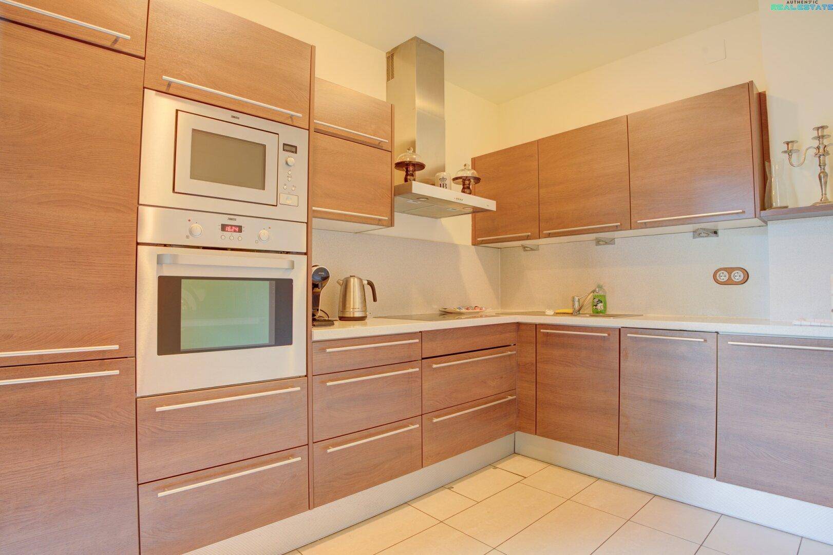 Moderne Einbauküche mit Holzfronten, integrierten Geräten und heller Arbeitsplatte, funktional und stilvoll.