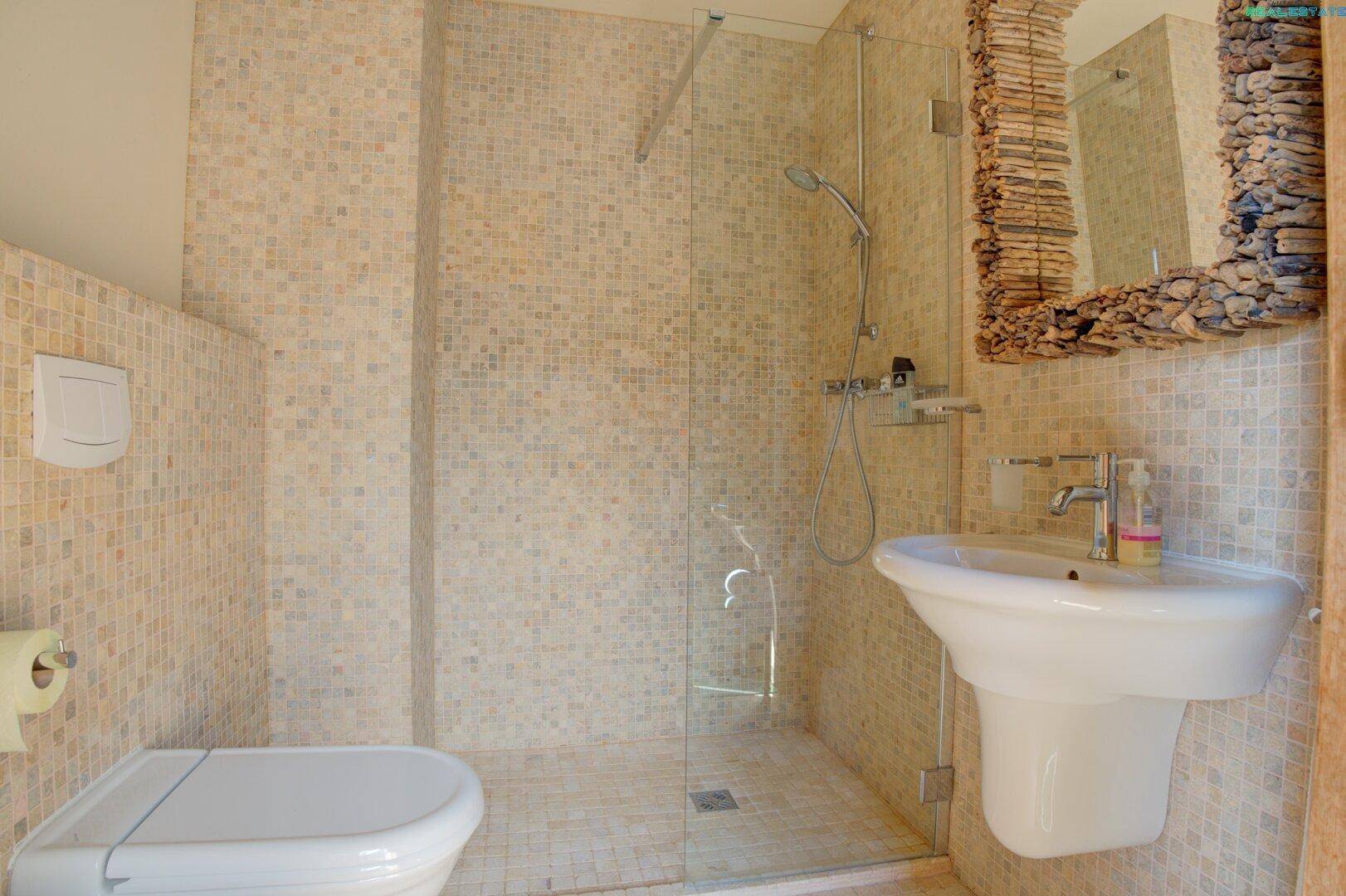 Modernes Badezimmer mit Mosaikfliesen, ebenerdiger Dusche und stilvollem Spiegel, hell und funktional.
