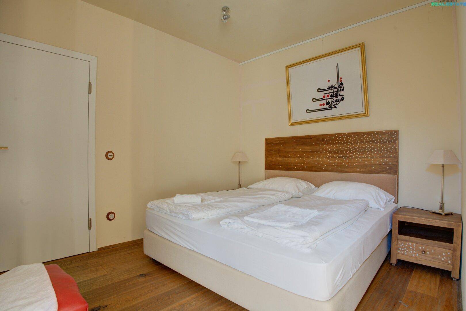 Gemütliches Schlafzimmer mit Doppelbett, Holzboden und traditioneller Dekoration, hell und einladend.