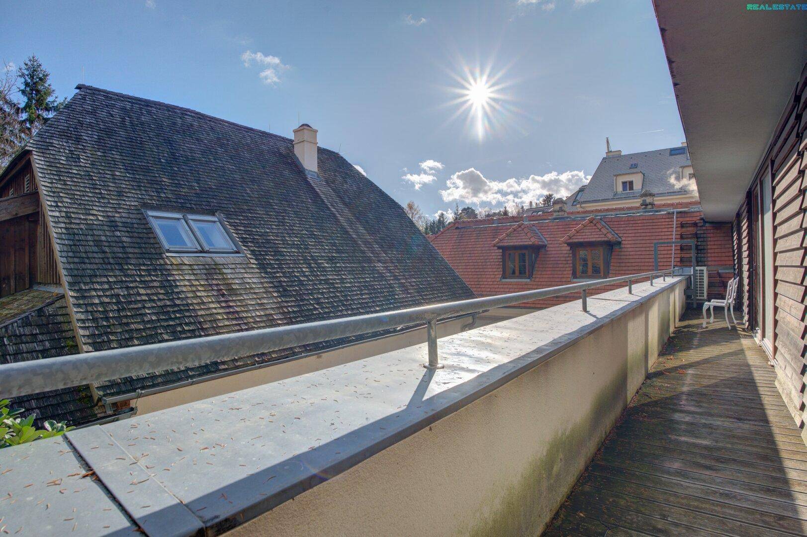 Langer Balkon mit Holzboden und Metallgeländer, bietet einen weiten Blick auf die Umgebung.