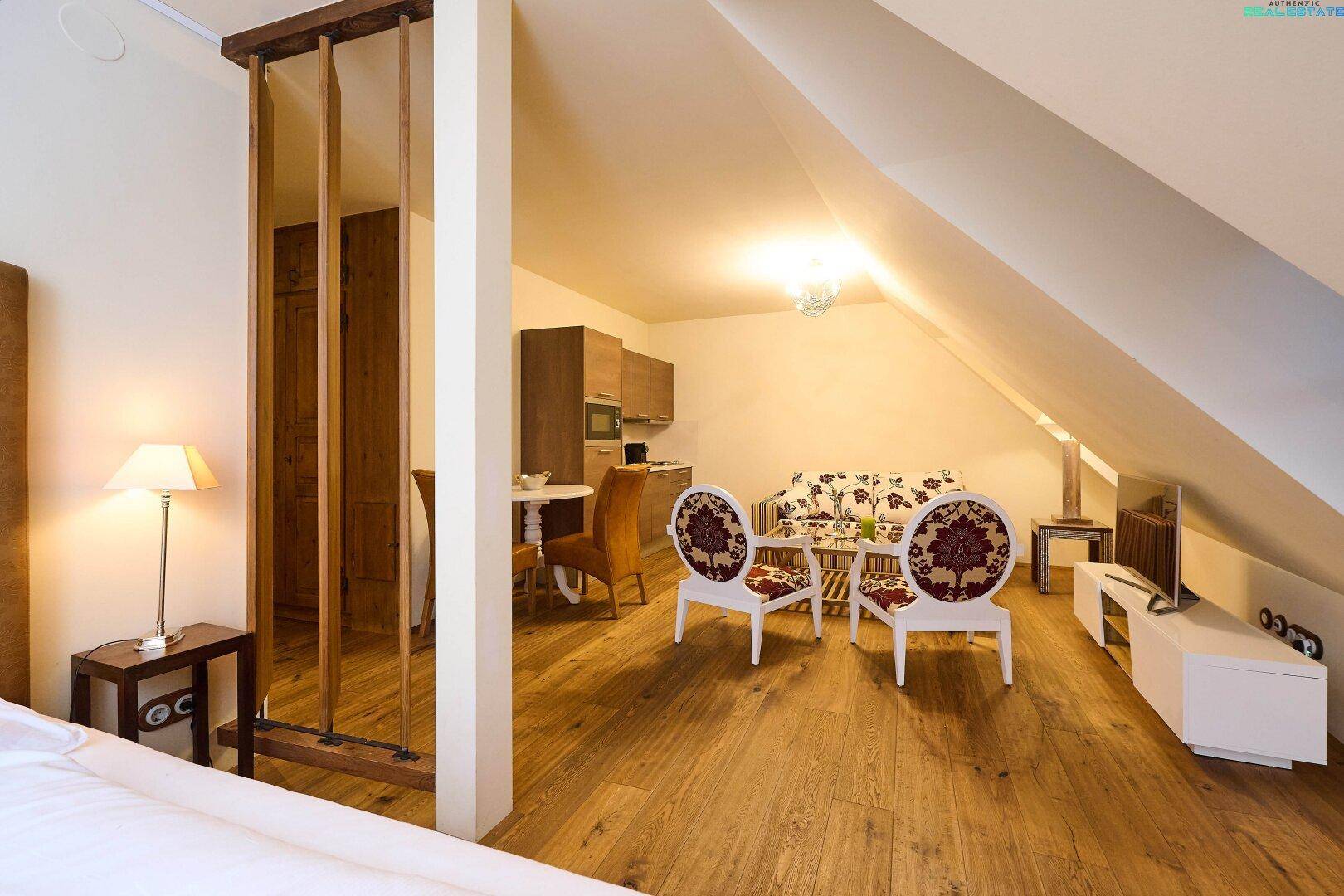 Helle Dachgeschosswohnung mit Holzboden, schrägen Wänden und integrierter Küchenzeile, gemütlich und modern.