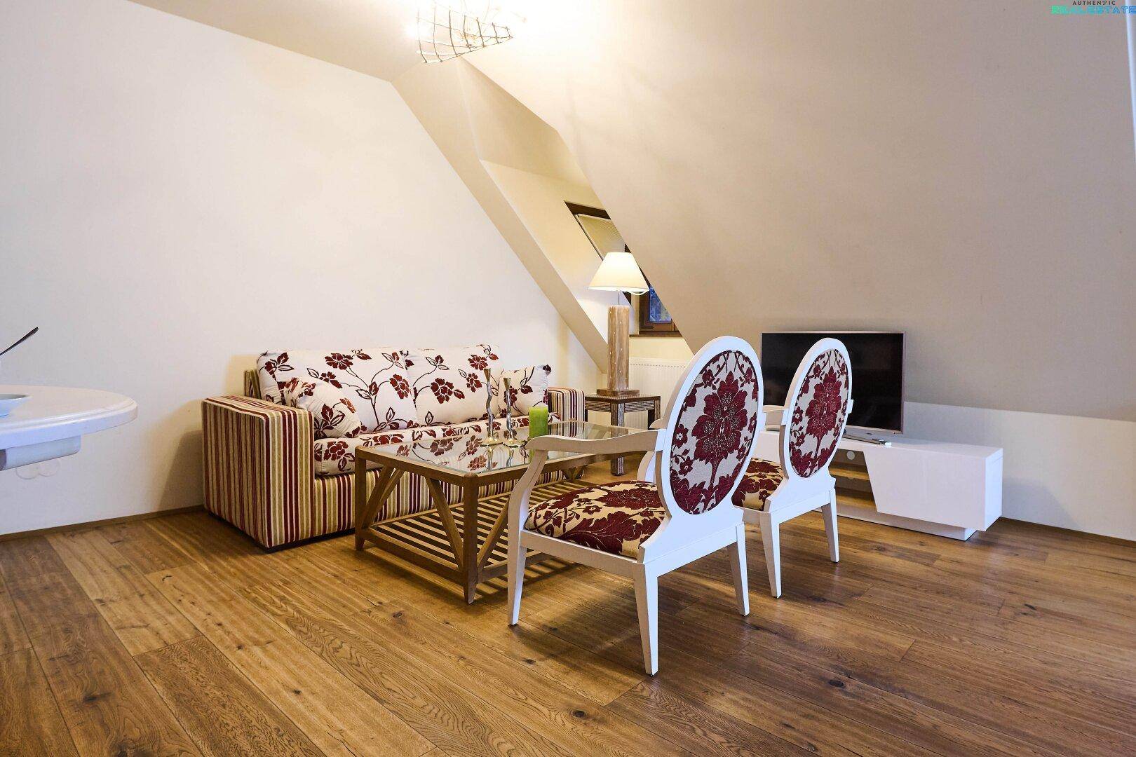 Gemütlicher Wohnbereich in der Dachgeschosswohnung mit Holzboden und stilvollen Möbeln, hell und einladend.