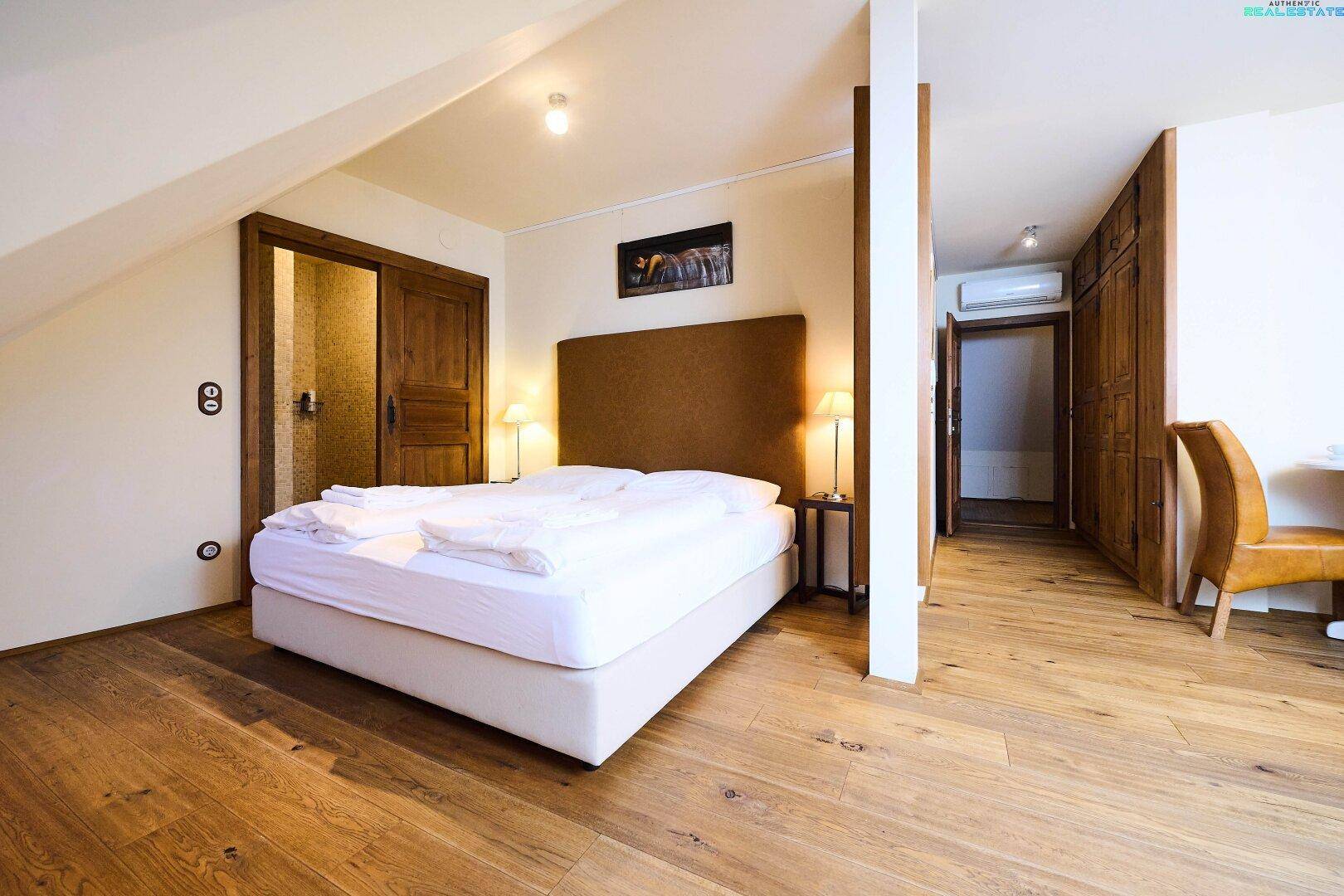 Schlafzimmer in der Dachgeschosswohnung mit Holzboden, Doppelbett und integrierten Holzschränken.