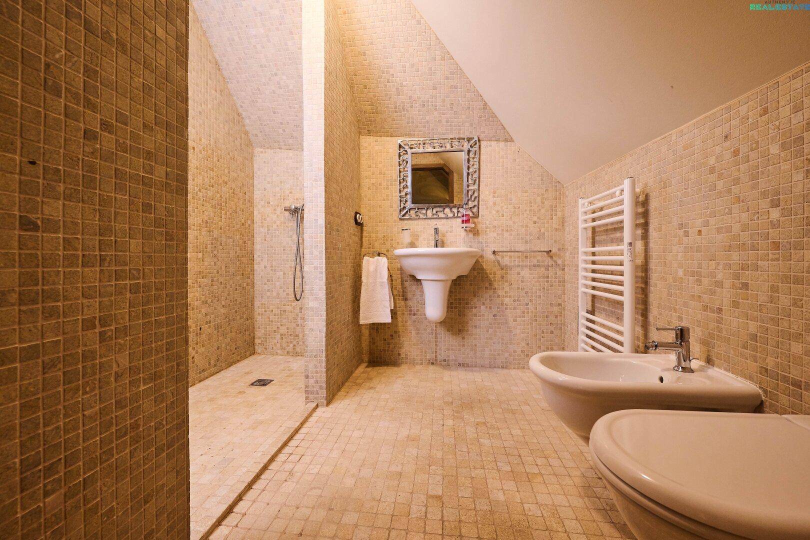 Modernes Badezimmer in der Dachgeschosswohnung mit Mosaikfliesen, ebenerdiger Dusche und Bidet.