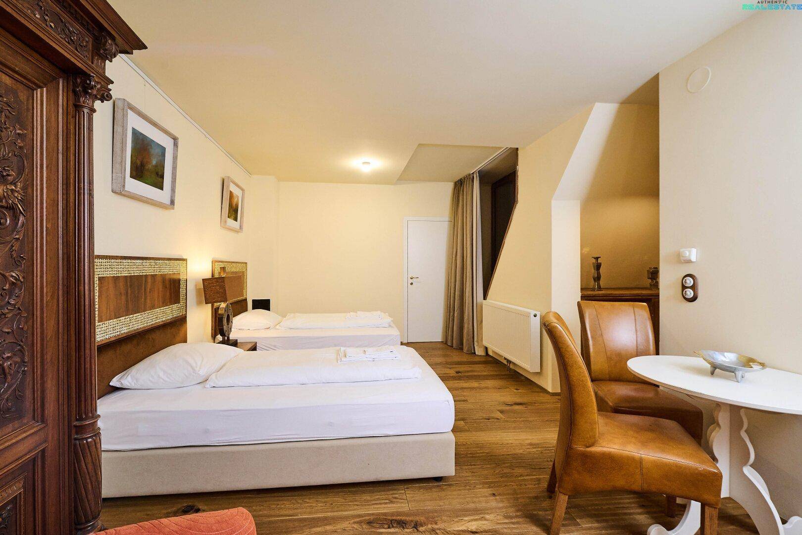 Helles Schlafzimmer in der Dachgeschosswohnung mit zwei Einzelbetten, Holzboden und Essbereich.