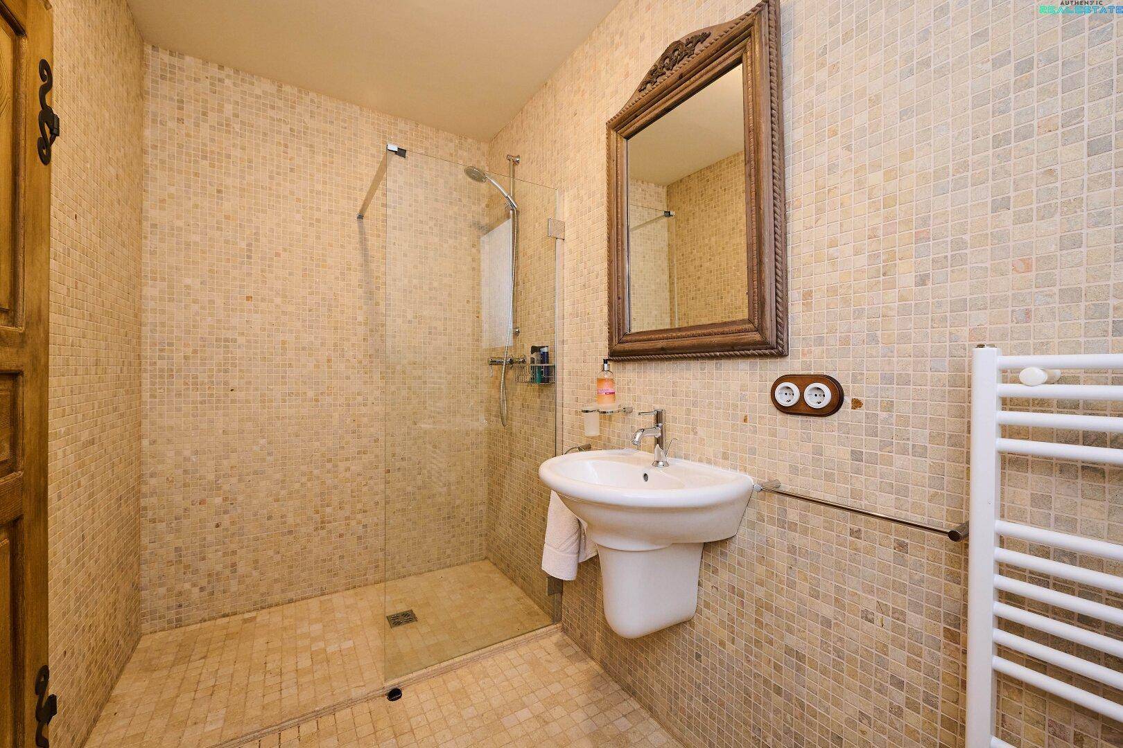 Modernes Badezimmer in der Dachgeschosswohnung mit Mosaikfliesen, ebenerdiger Dusche und beheiztem Handtuchhalter.