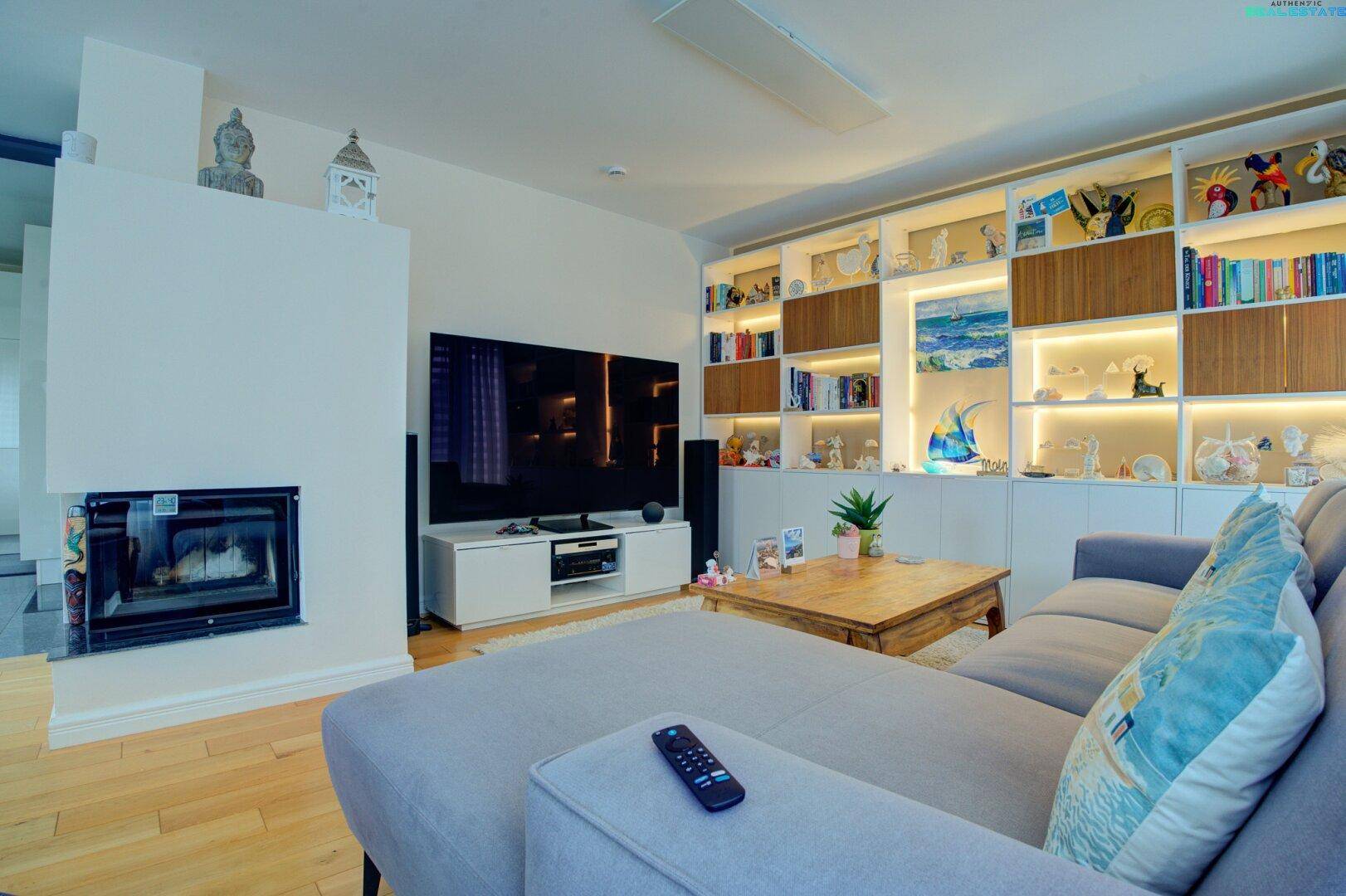 Modernes Wohnzimmer mit integriertem Kamin, großem Fernseher und Holzboden.