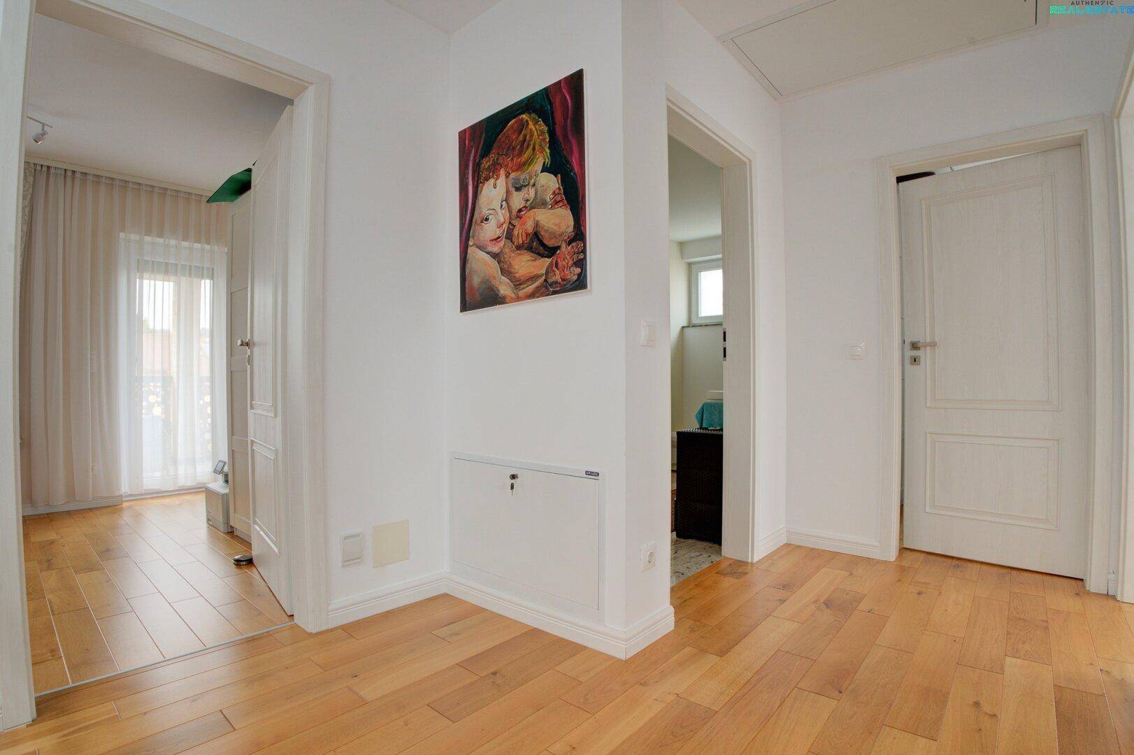 Heller Flur mit Holzboden, weißen Wänden und Zugang zu verschiedenen Räumen.