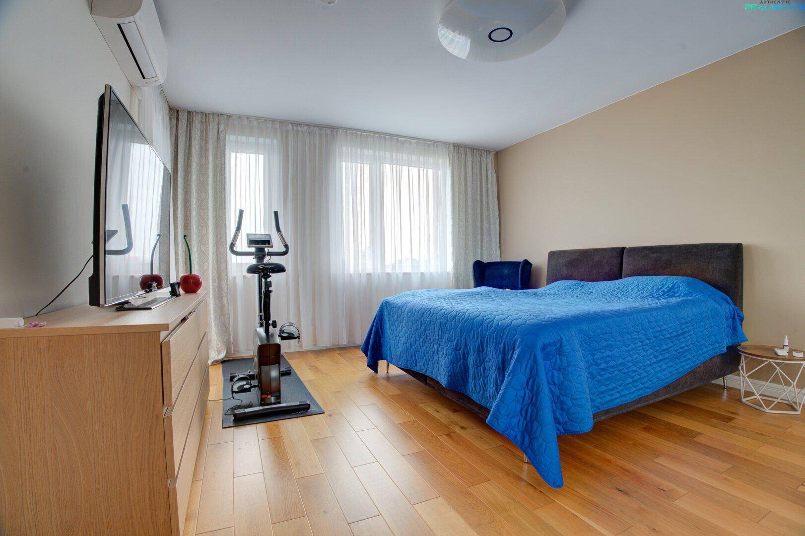Geräumiges Schlafzimmer mit Holzboden, Doppelbett, Heimtrainer und Klimaanlage.