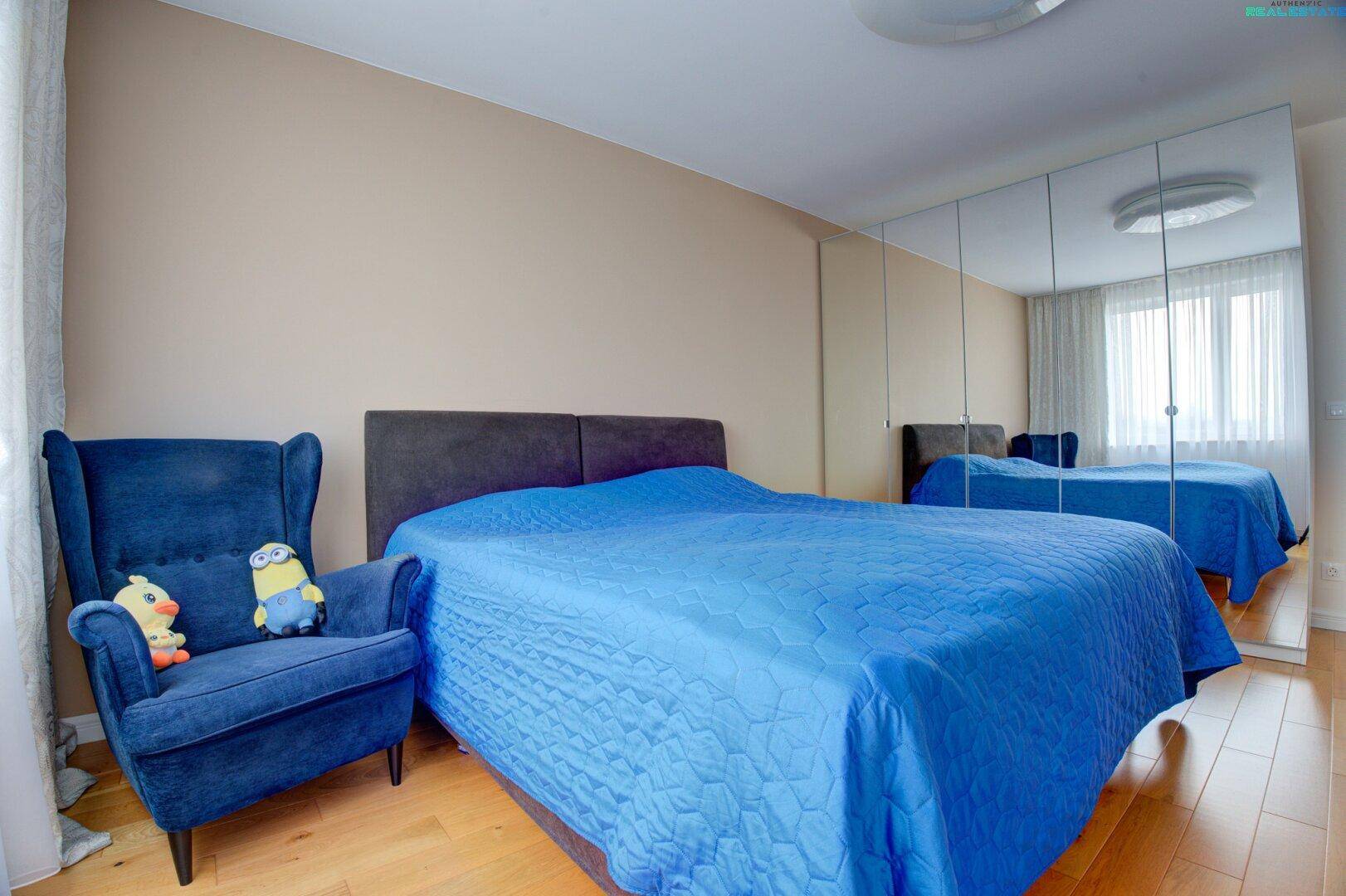 Helles Schlafzimmer mit Holzboden, Doppelbett und großer Spiegelfront.