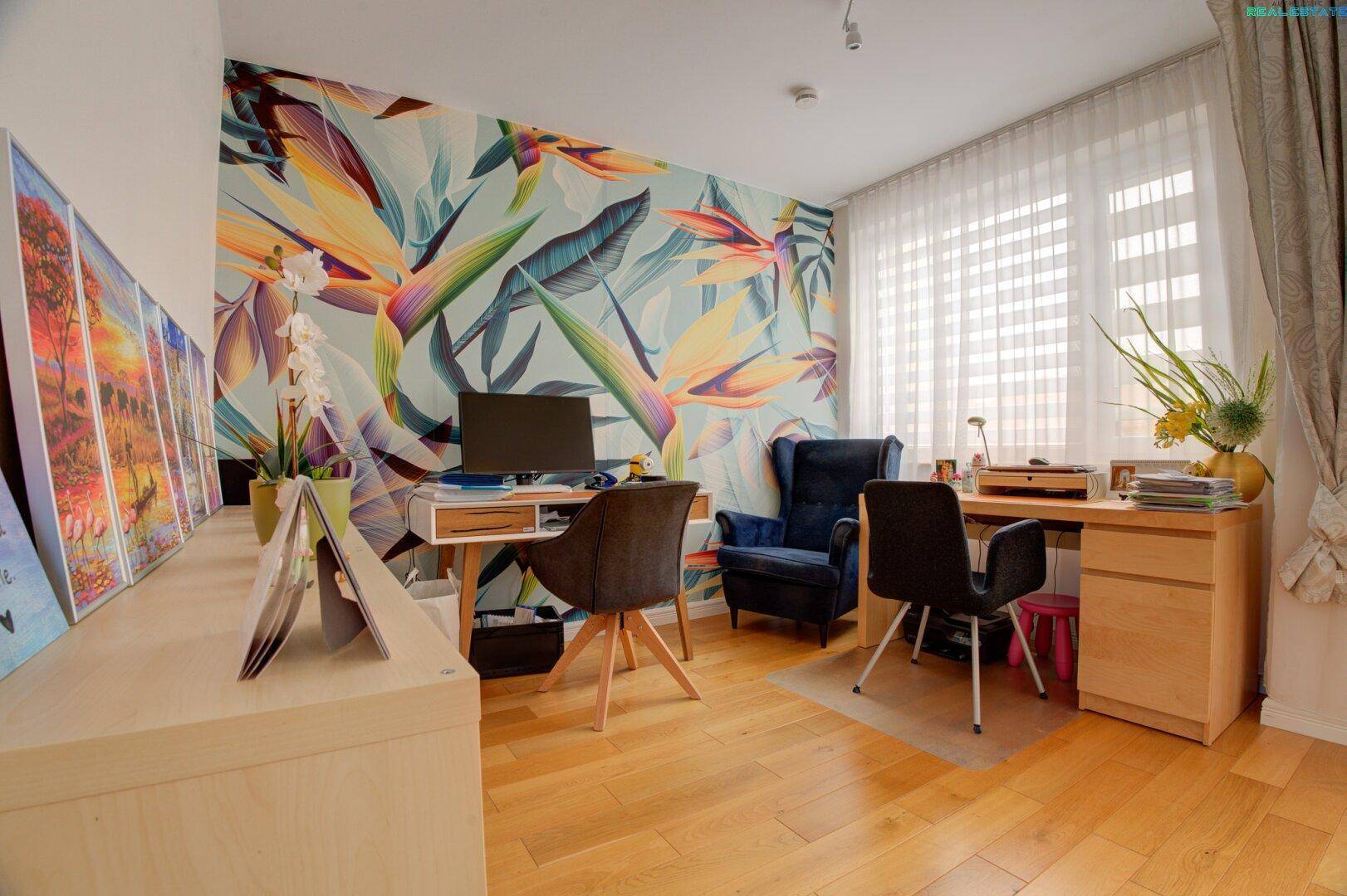 Kreatives Arbeitszimmer mit Holzboden, Schreibtisch und auffälliger tropischer Tapete.