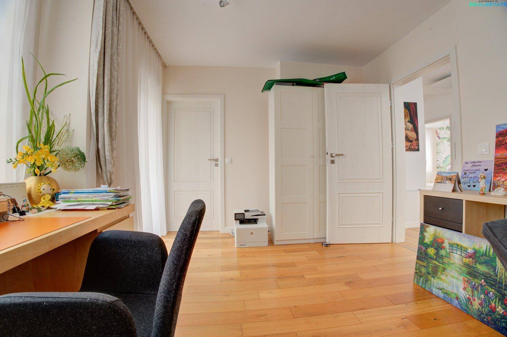 Arbeitszimmer mit Holzboden, Schreibtisch und weißem Kleiderschrank.