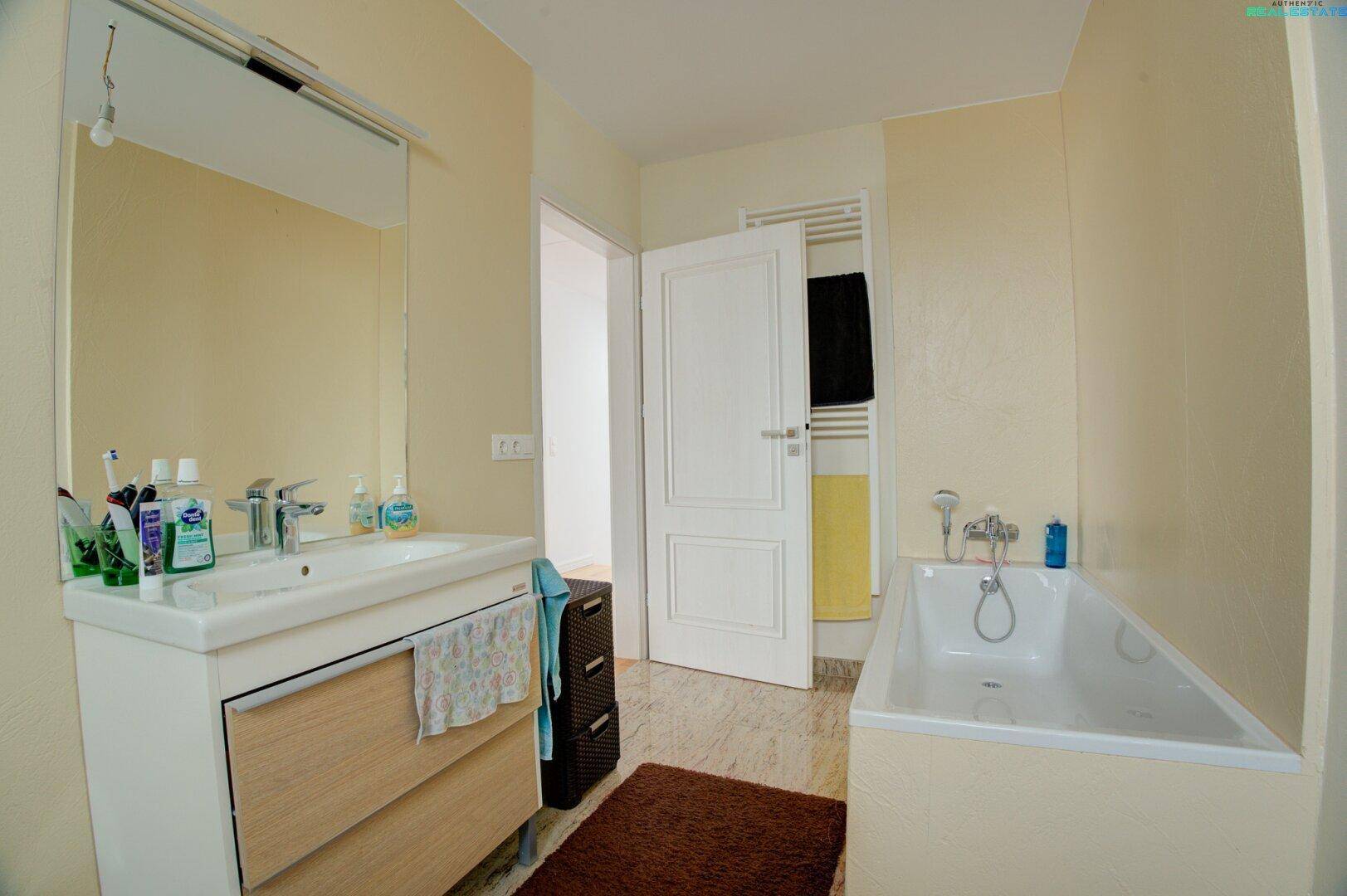 Helles Badezimmer mit Badewanne, Waschbecken und beheiztem Handtuchhalter.