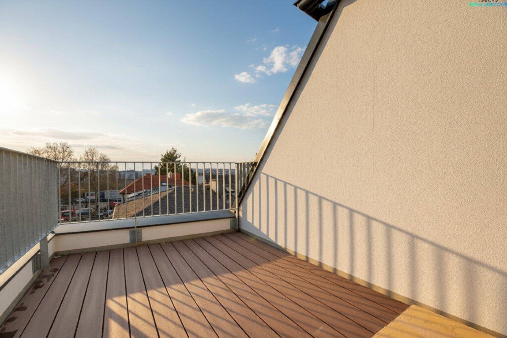 Balkon im Dachgeschoss mit Holzboden und Metallgeländer, bietet weite Aussicht über die Umgebung.