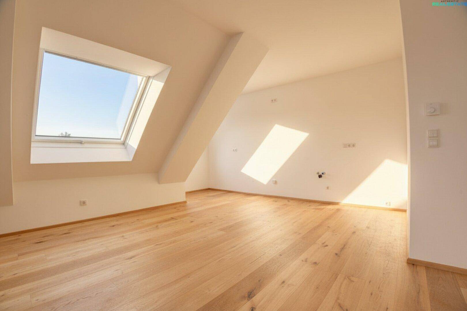 Helles Schlafzimmer im Dachgeschoss mit Holzboden und zwei Dachfenstern, die viel Licht hereinlassen.