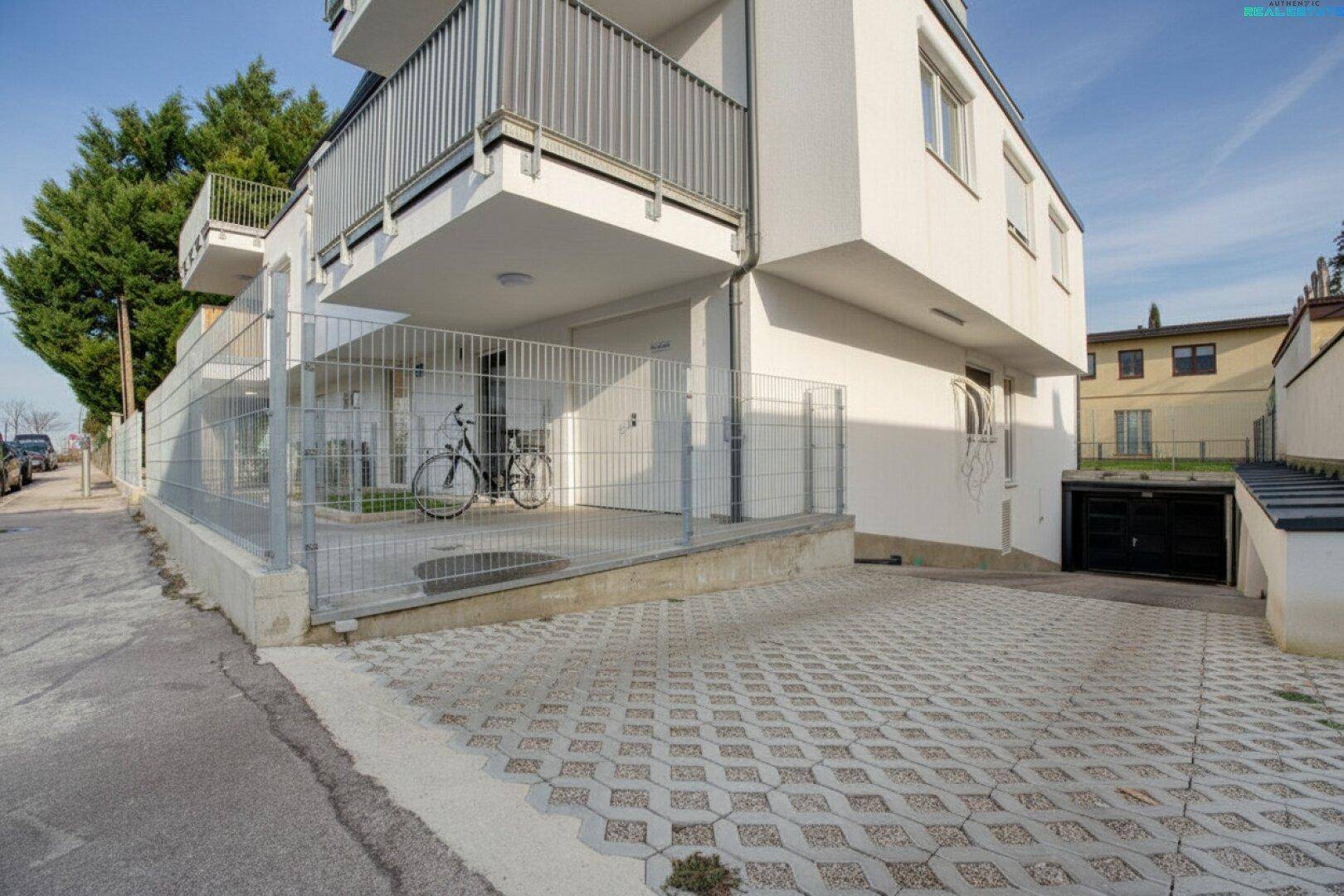 Moderne Wohnanlage mit Tiefgaragenzufahrt und einem Fahrradabstellplatz im Freien.