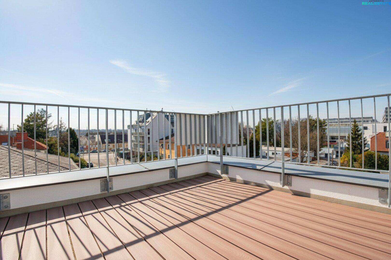 Große Dachterrasse mit Holzboden und Metallgeländer, bietet weite Aussicht über die umliegende Stadtlandschaft.