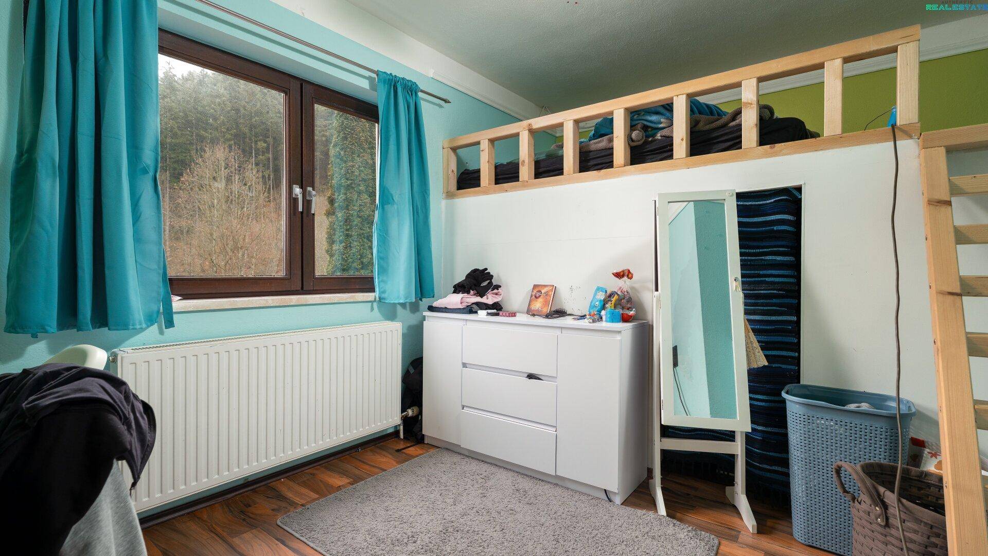 Kinderzimmer mit Hochbett, Kommode und Fenster mit Blick ins Grüne.