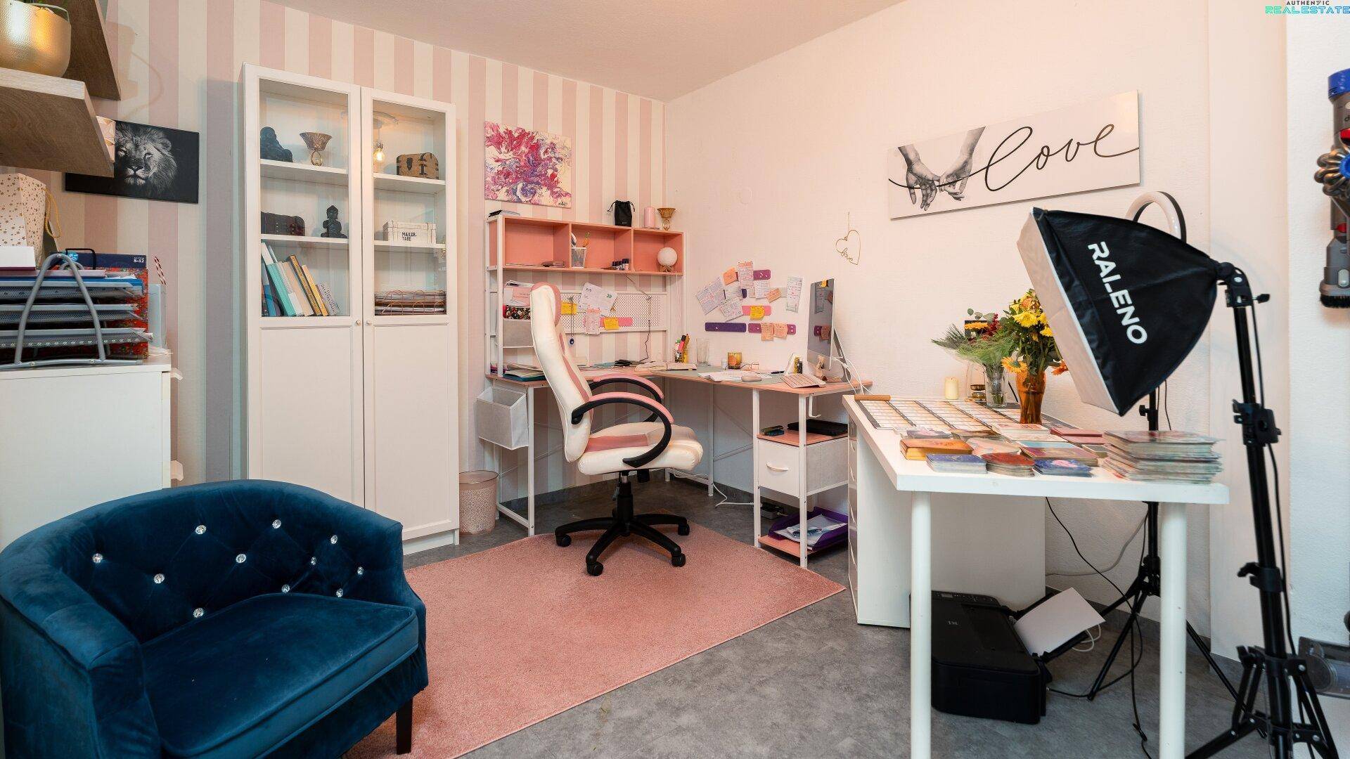 Helles Arbeitszimmer mit Schreibtisch, Bürostuhl und dekorativer Tapete.