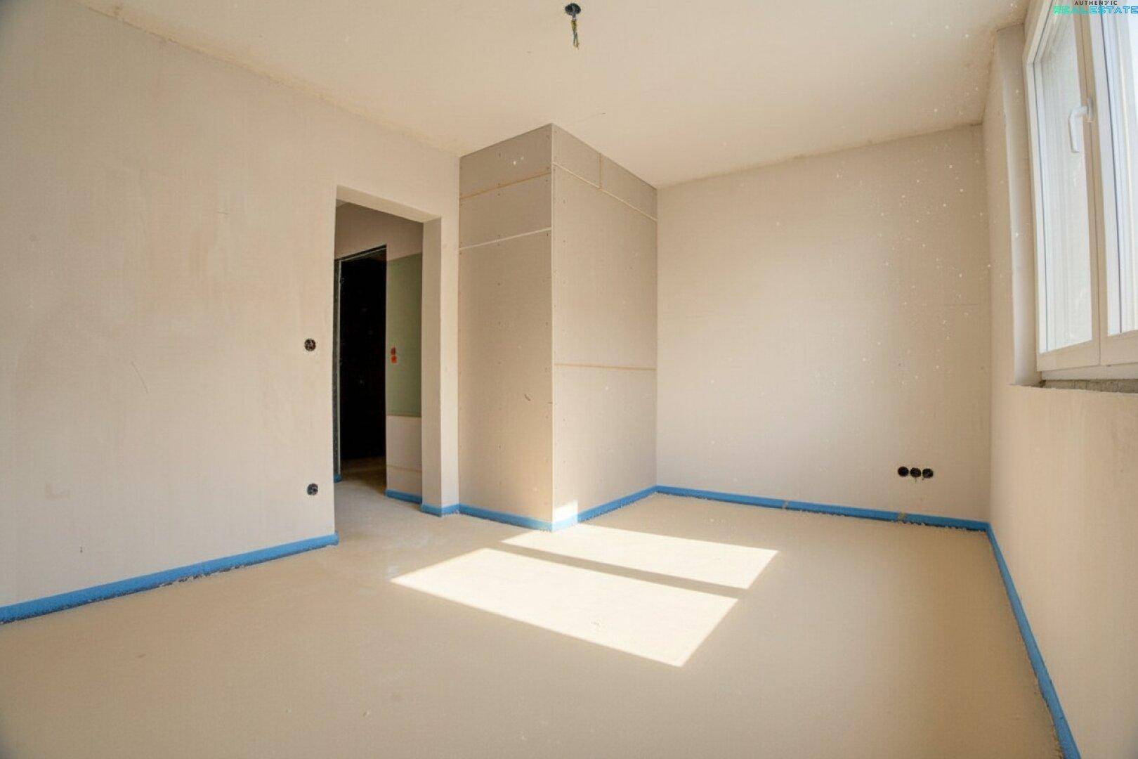 Schlafzimmer im Rohbau mit Fenster und vorbereiteten Wänden, ideal für die individuelle Gestaltung.