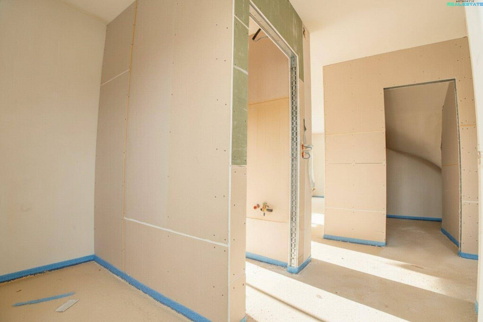 Flurbereich im Rohbau mit Trockenbauwänden und vorbereiteten Türöffnungen.